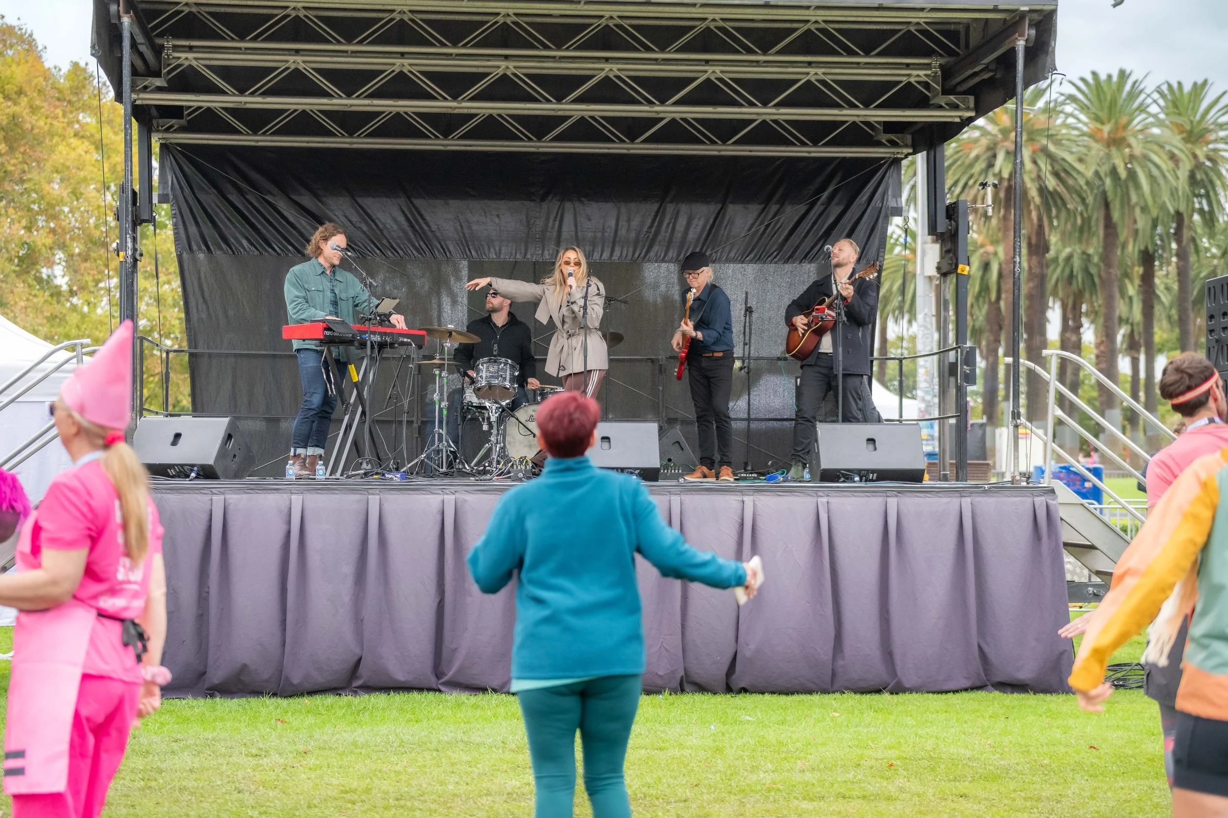 Racegoers dance as a band performs on stage.