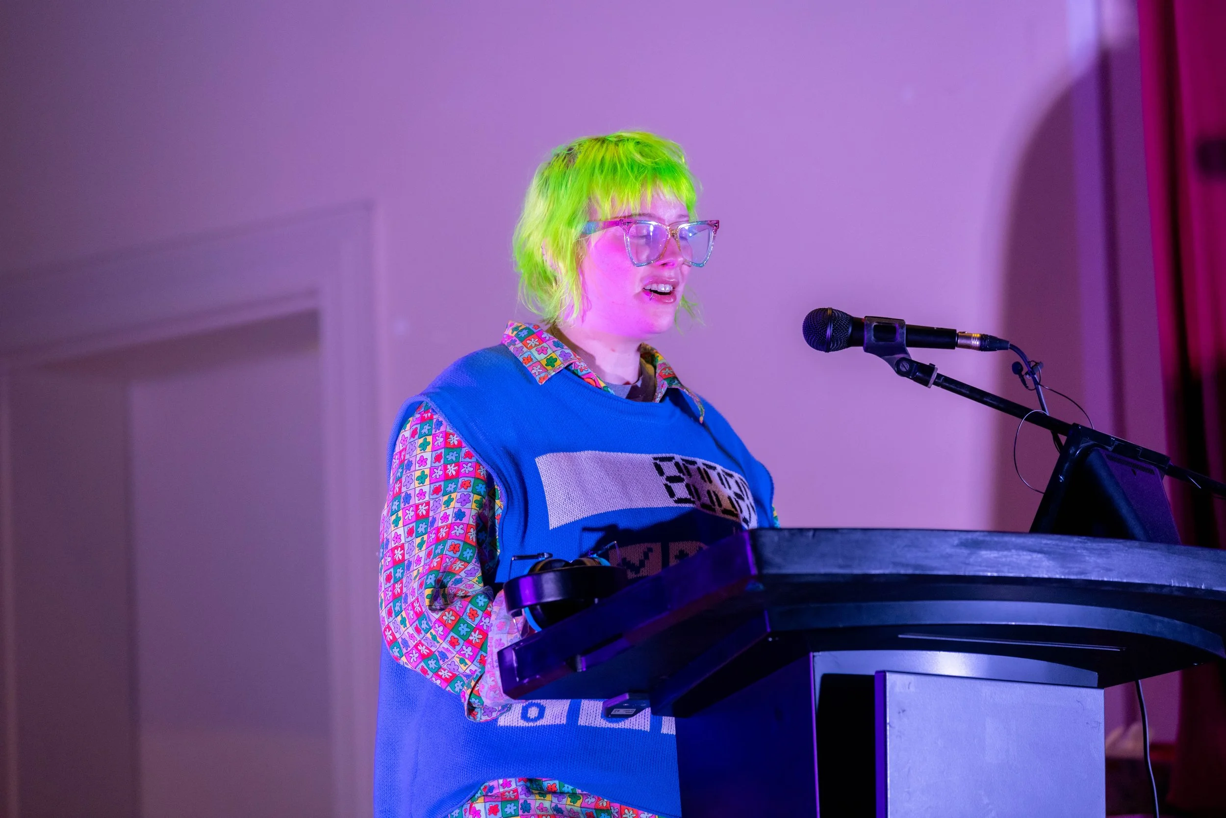 Alex Creece has green hair and speaks from behind a lecturn.