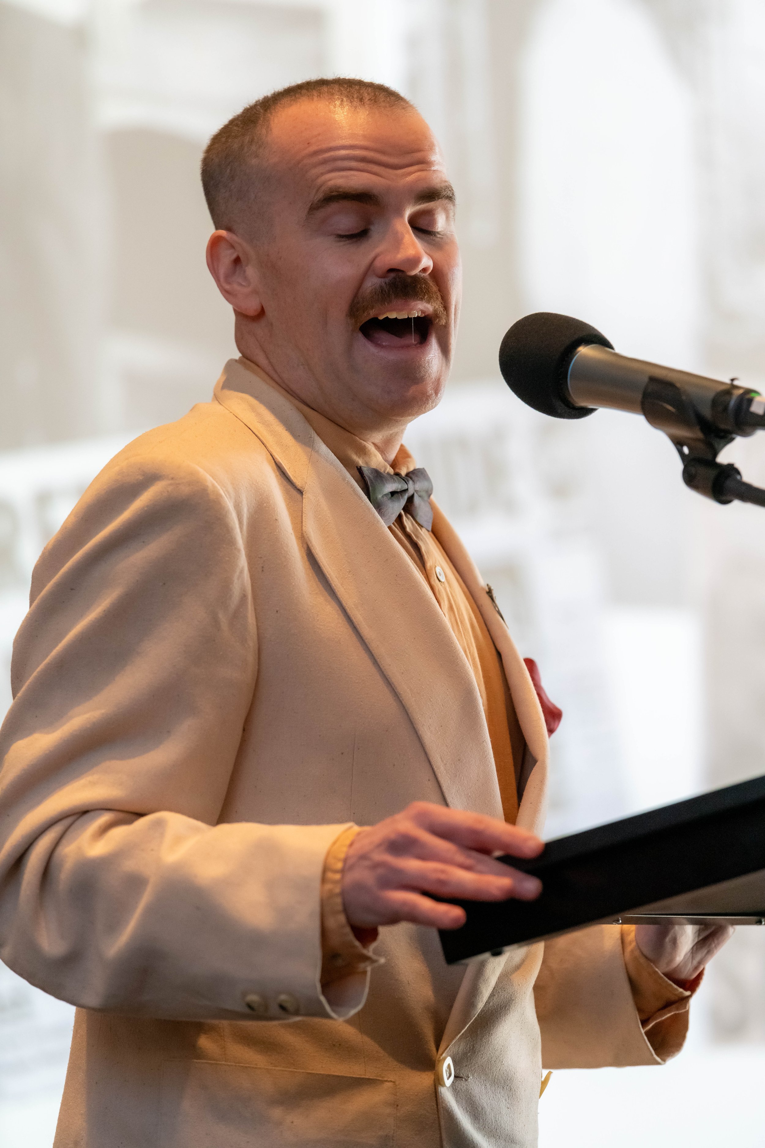 Jono Butler stands in costume and speaks into a microphone.