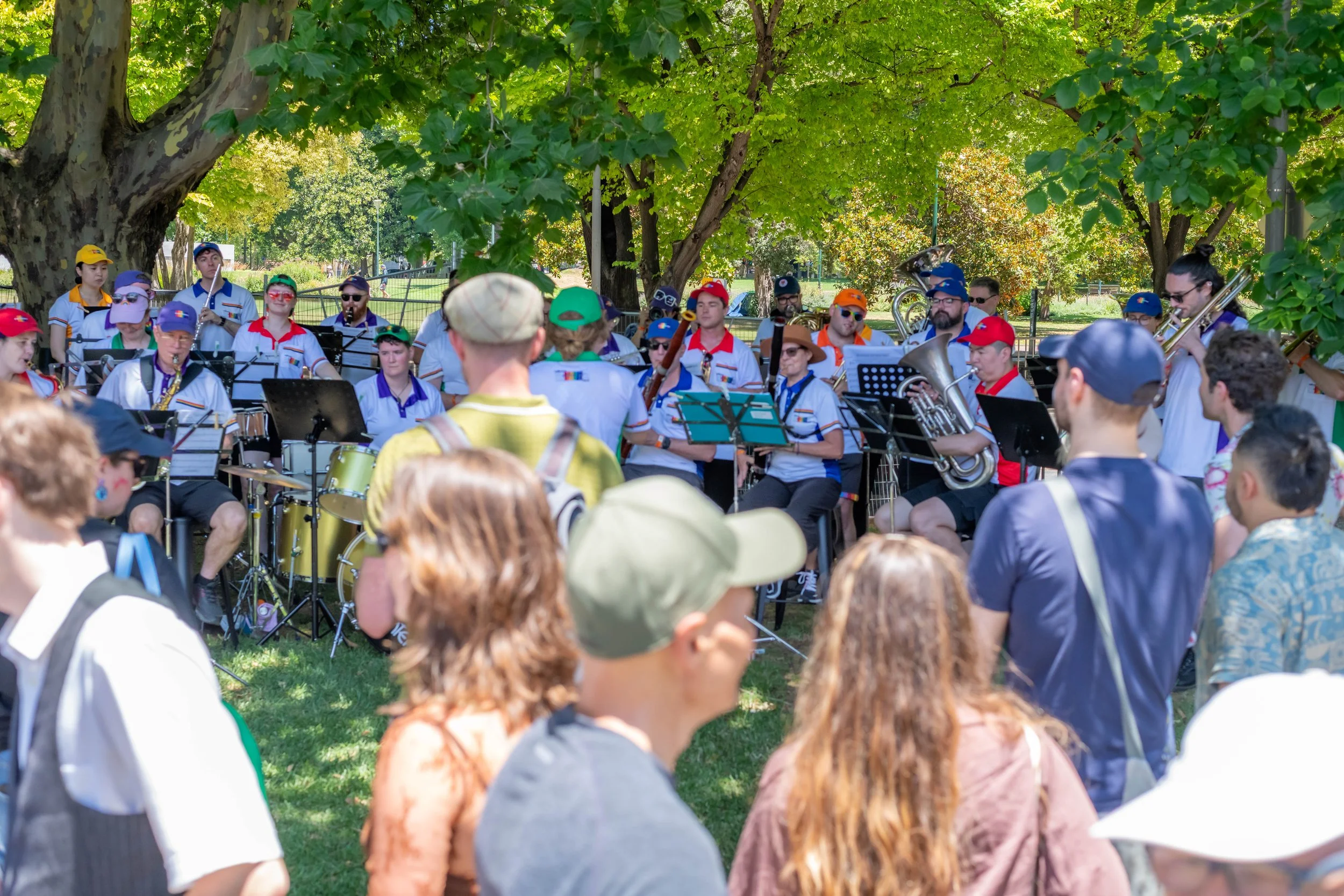 Humans watch the Melbourne Rainbow Band as they perform.