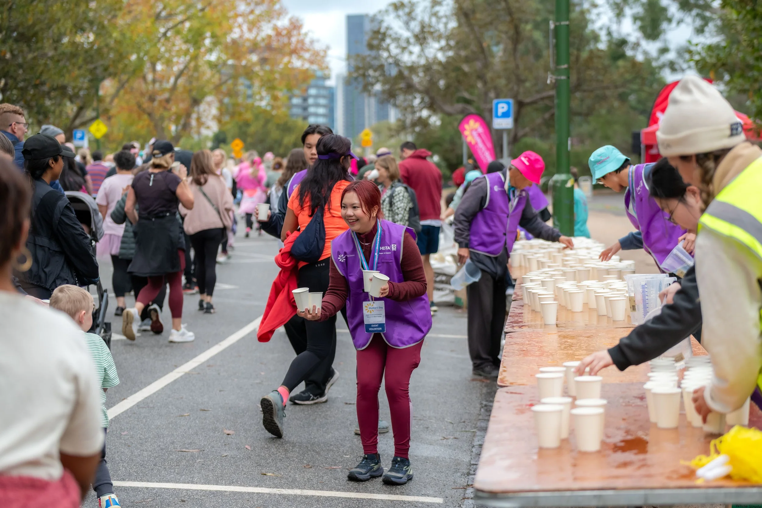 A volunteer holds cups of water for passing racegoers.