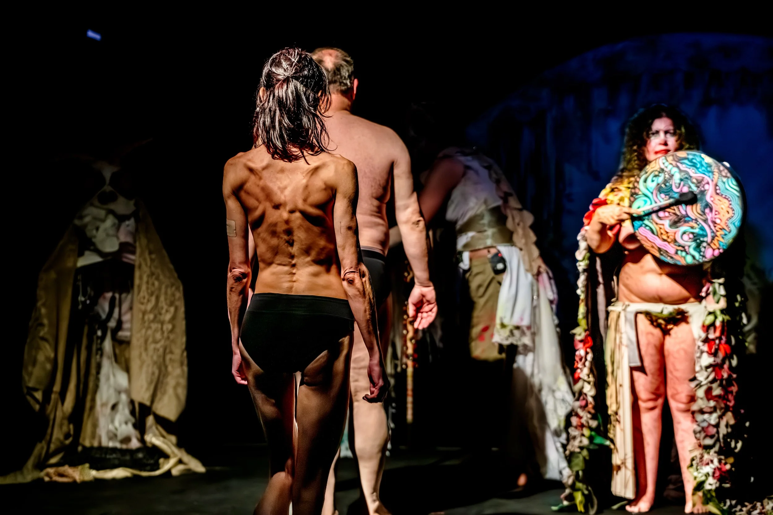 Two performers wearing only underwear walk to the stage whilst Jessie Ngaio bangs an ornately painted drum.
