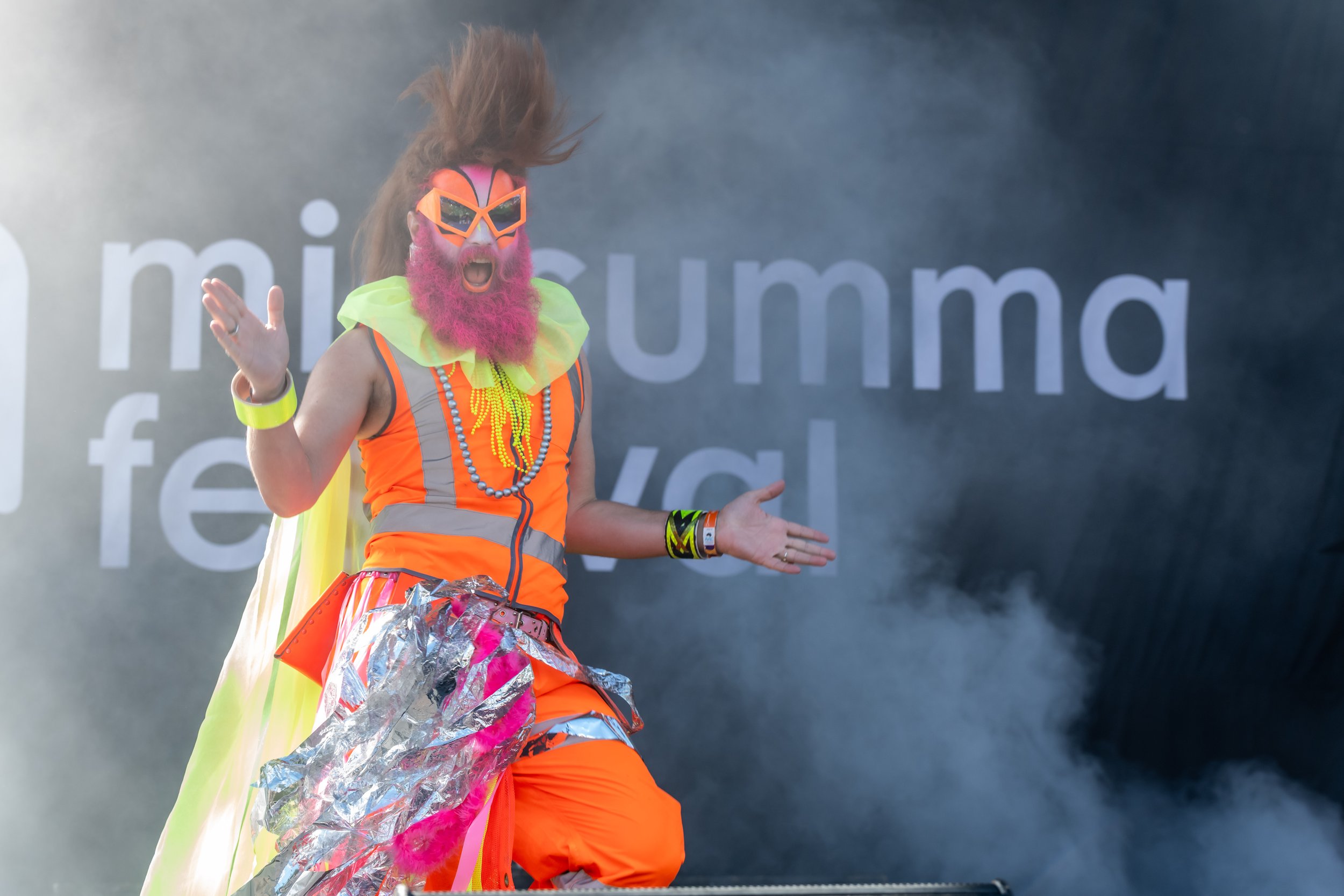 A human in hi-vis has their mouth open and is dancing through smoke.