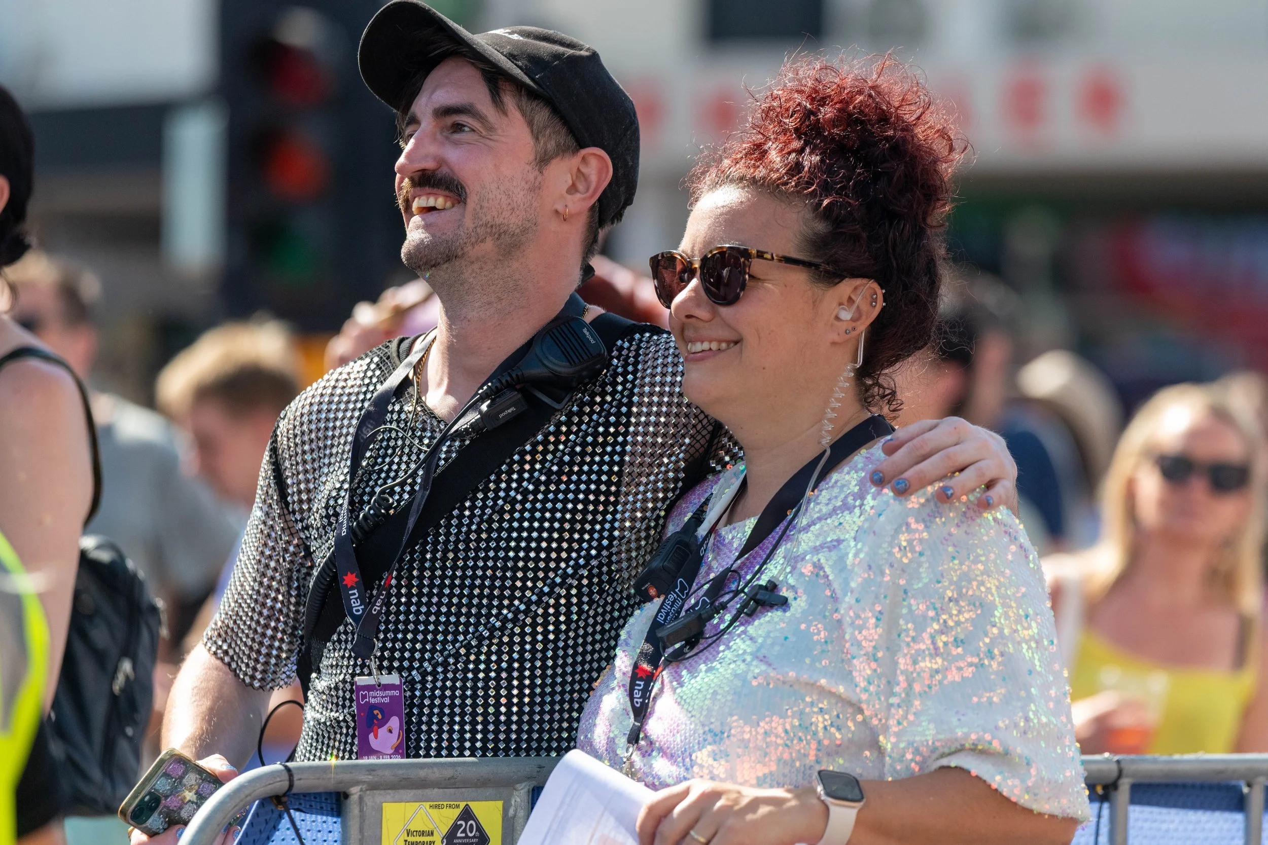 Two Midsumma Festival staff members. One wears a black glittery top, the other a white glittery top.