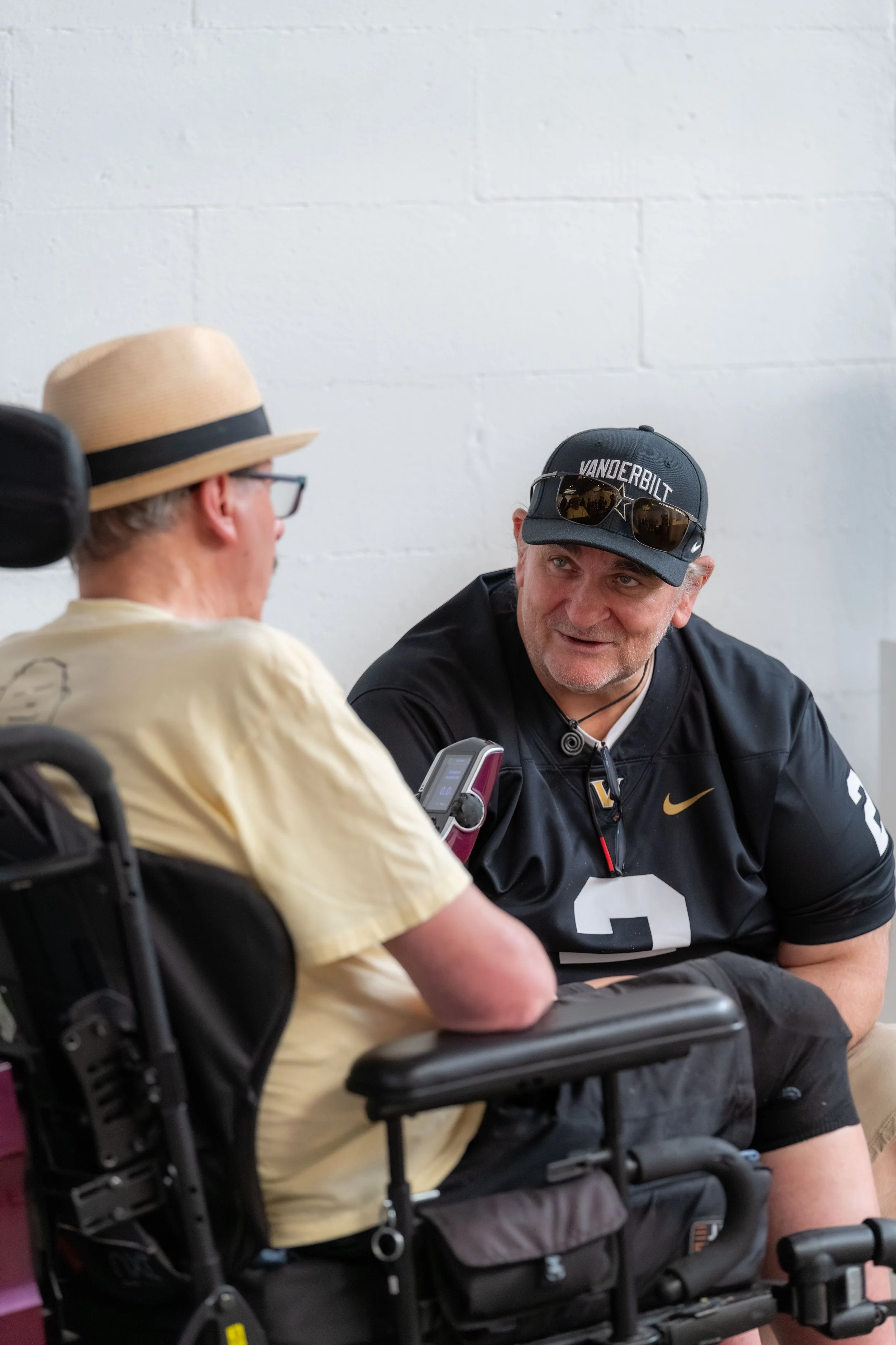 Two humans, one in a wheelchair, chat with each other.