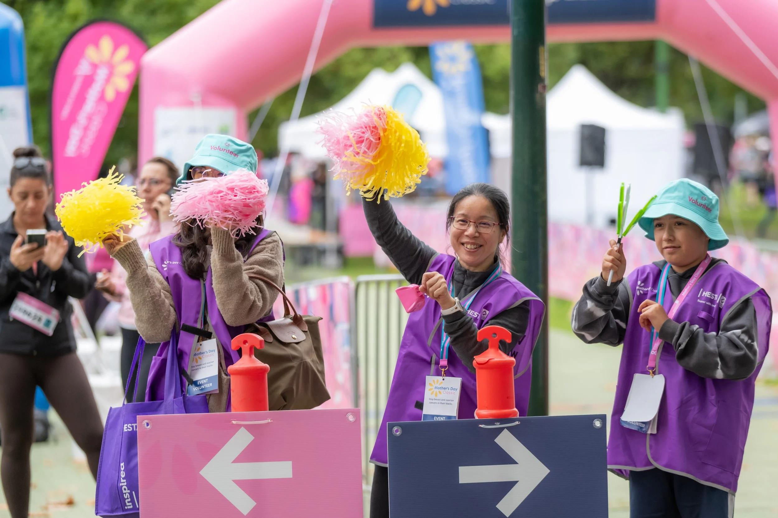 Volunteers wave pom poms and clack hands near the finish line.