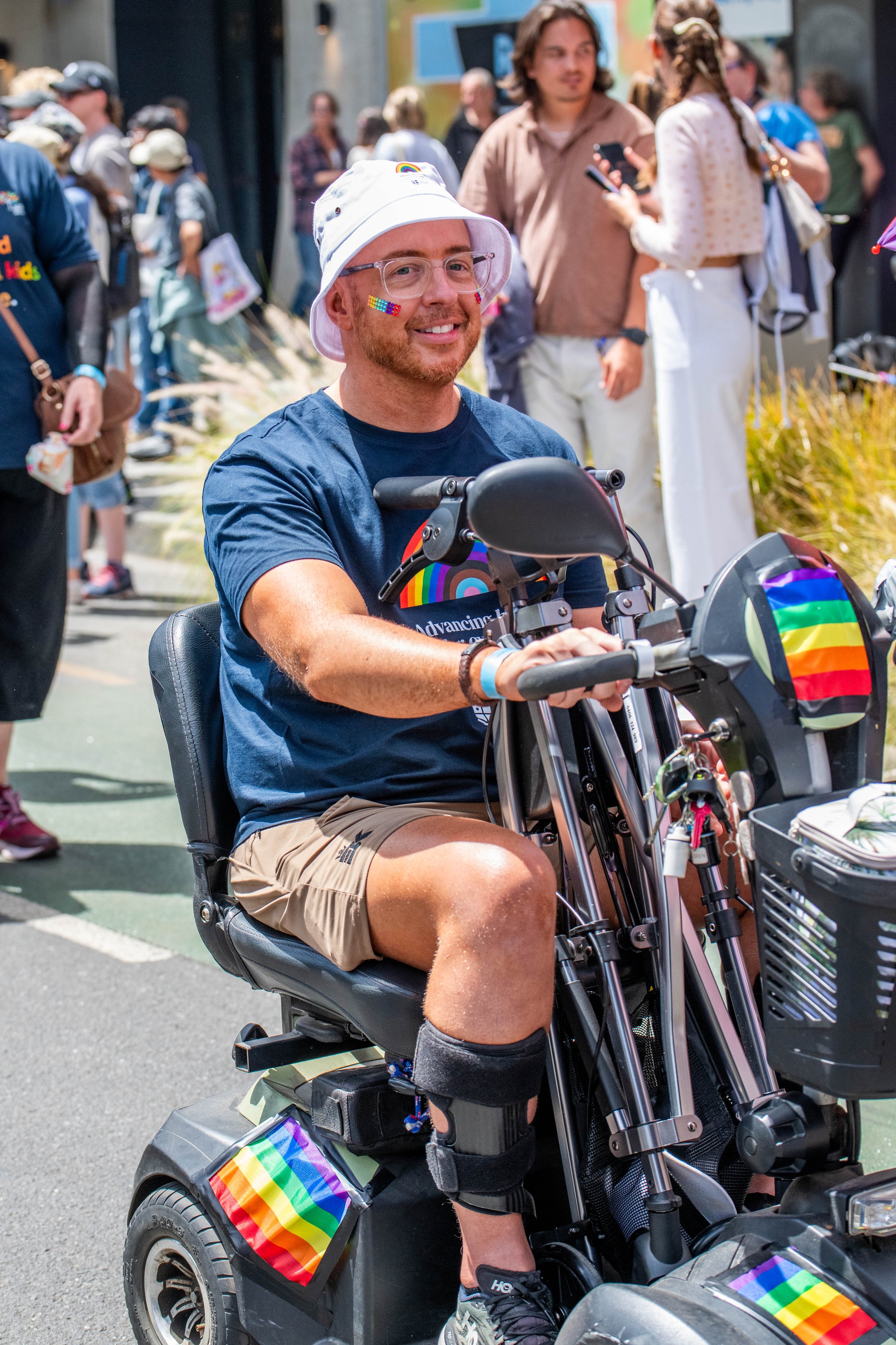 A human in a mobility device smiles at the camera.