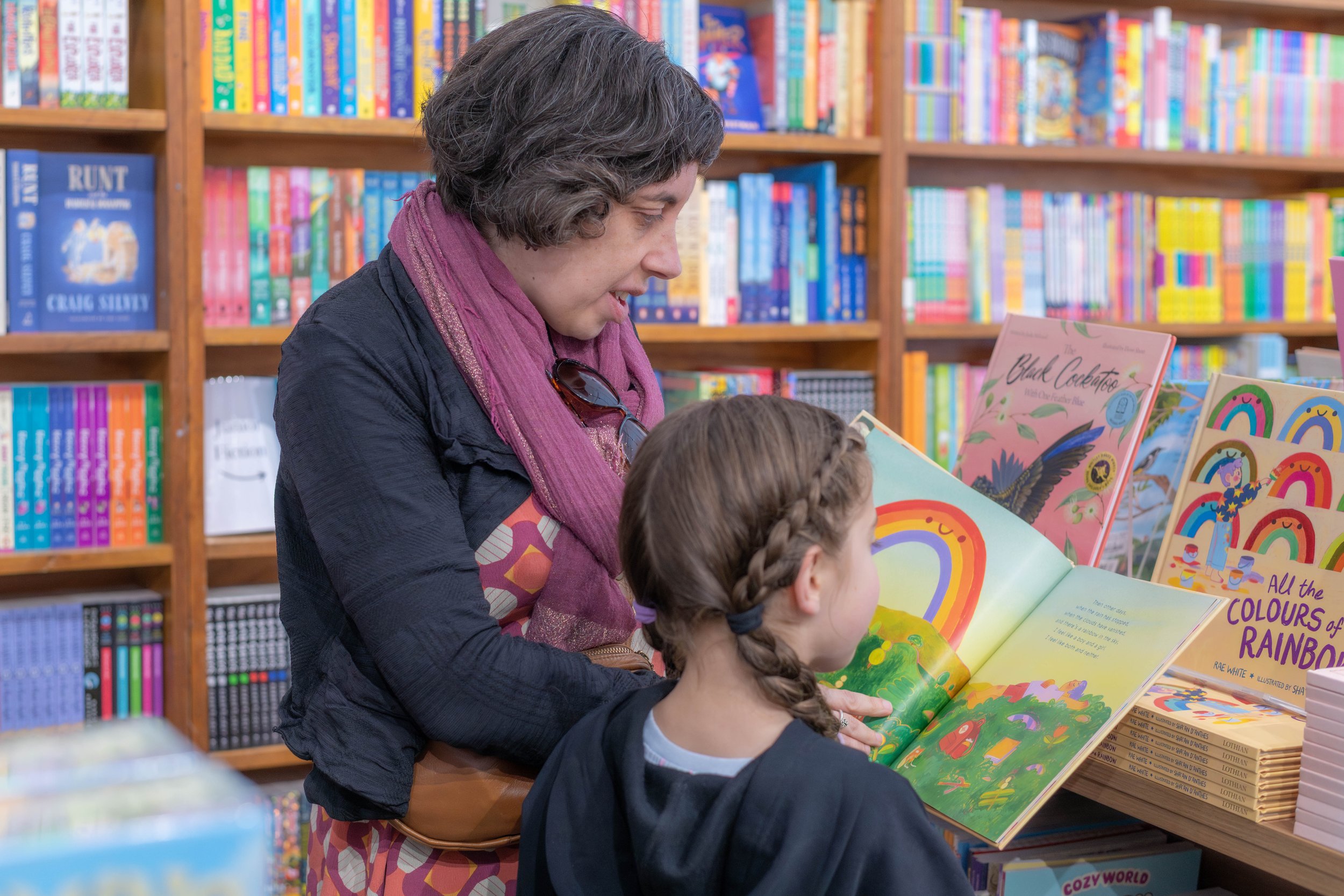 A parent shows an opened picture book to a child.