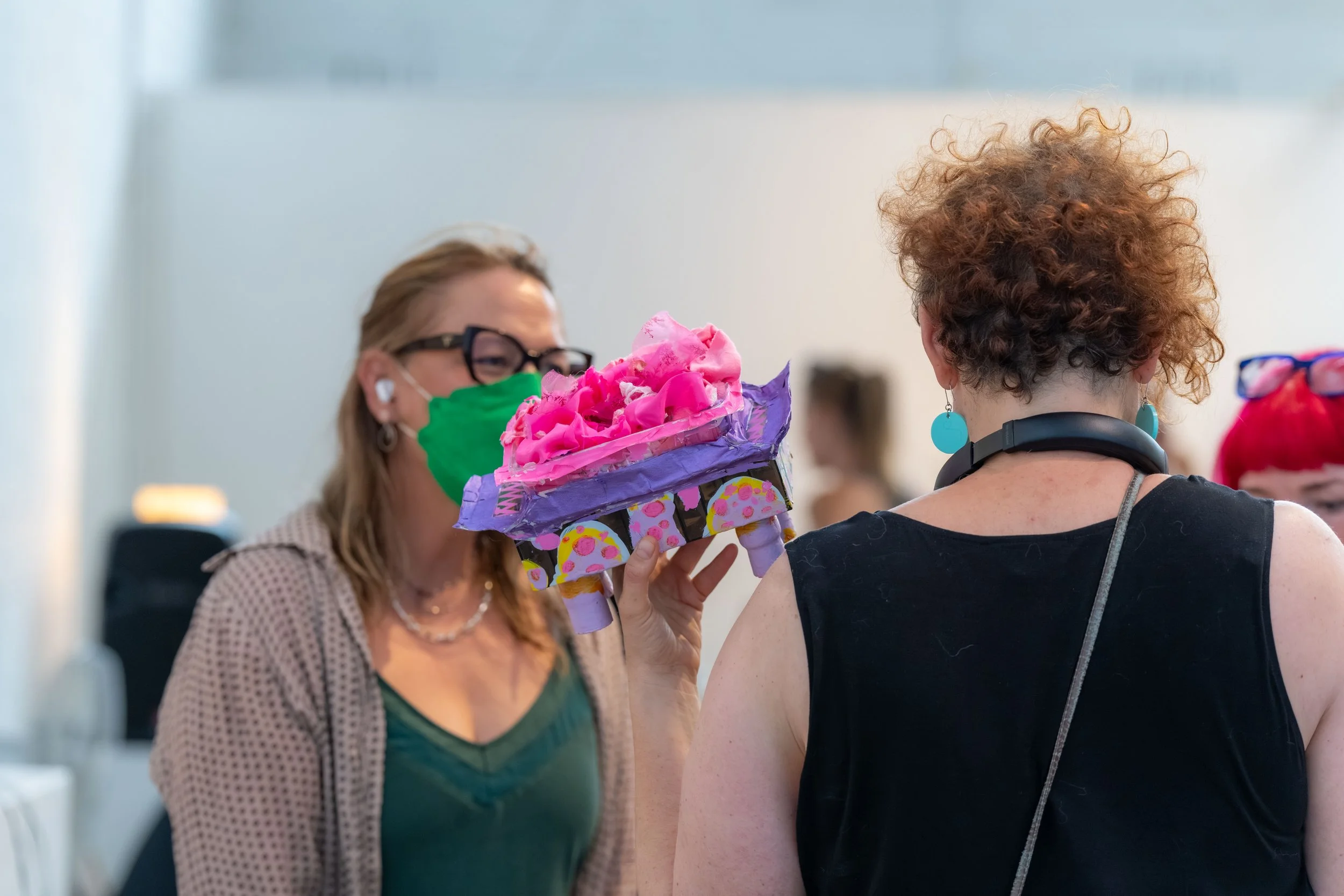 An artist holds up a colourful piece.