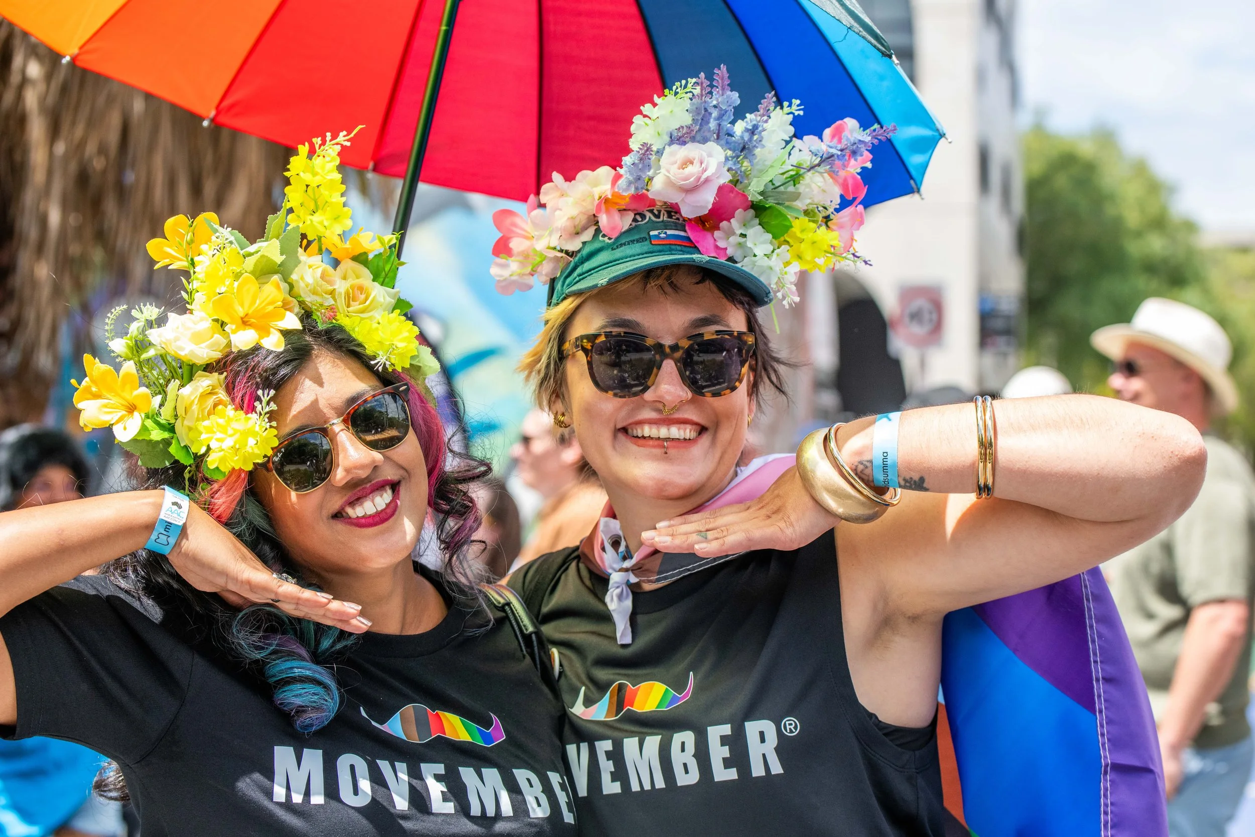 Two humans from Movember wearing flower headresses pose for the camera.