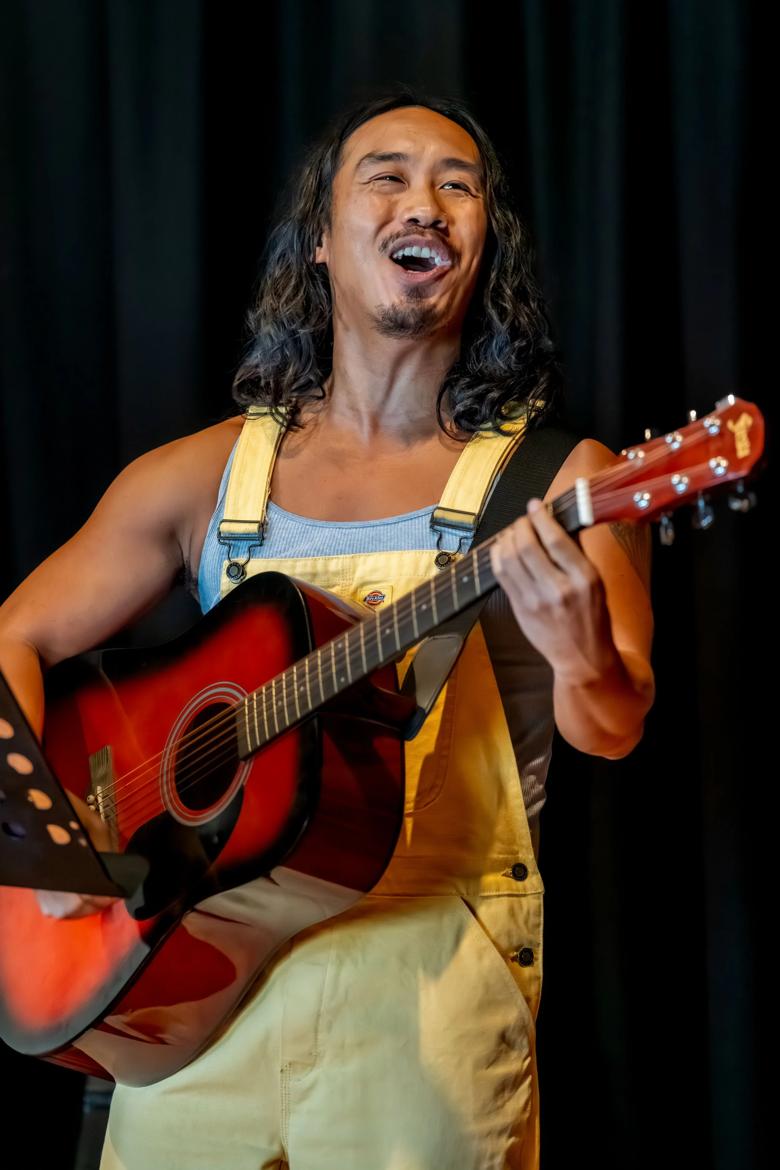 A human sings whilst playing guitar.