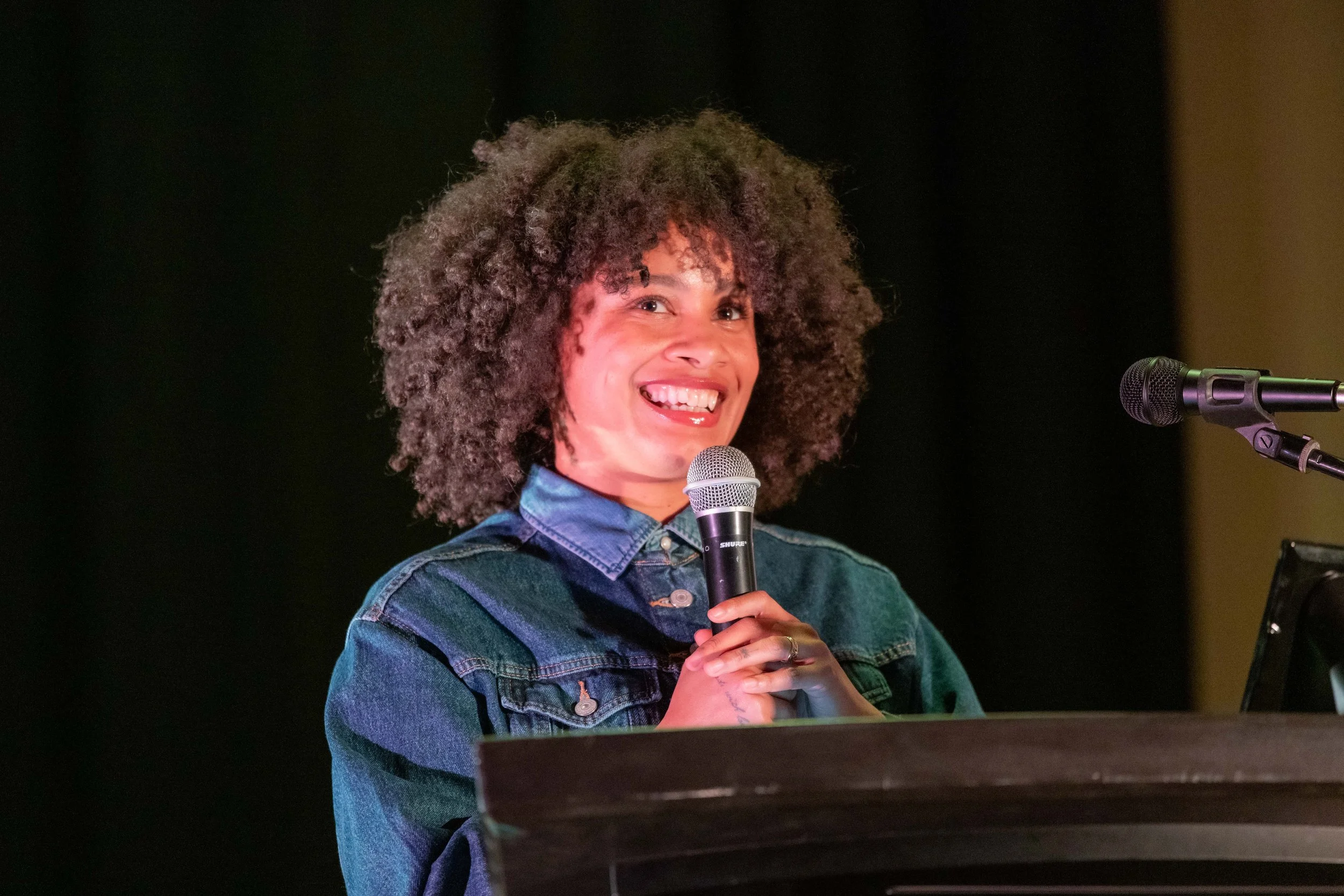 Aurelia St Clair smiles whilst holding a microphone.