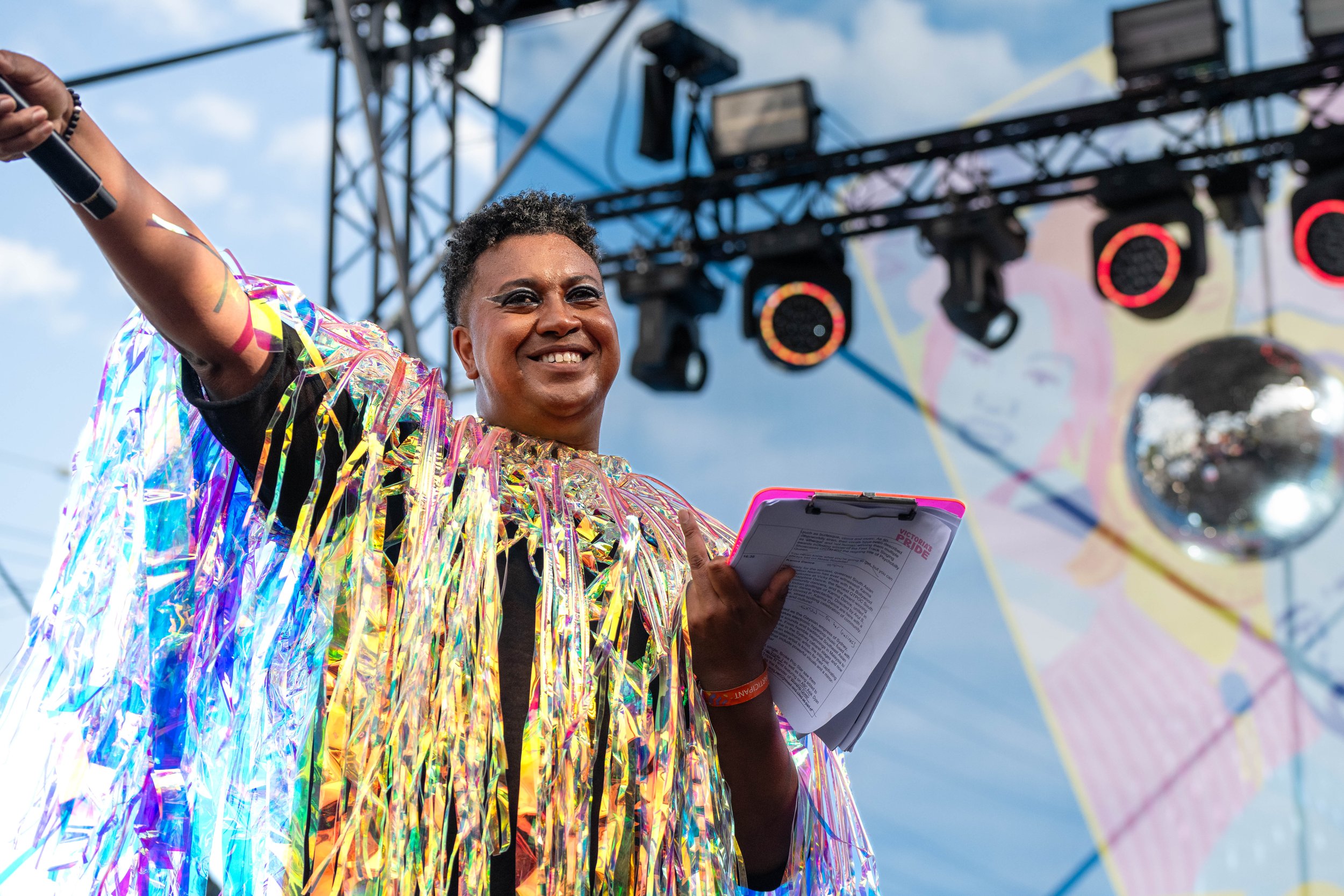 Samuel Gaskin holds the microphone to the crowd and smiles.