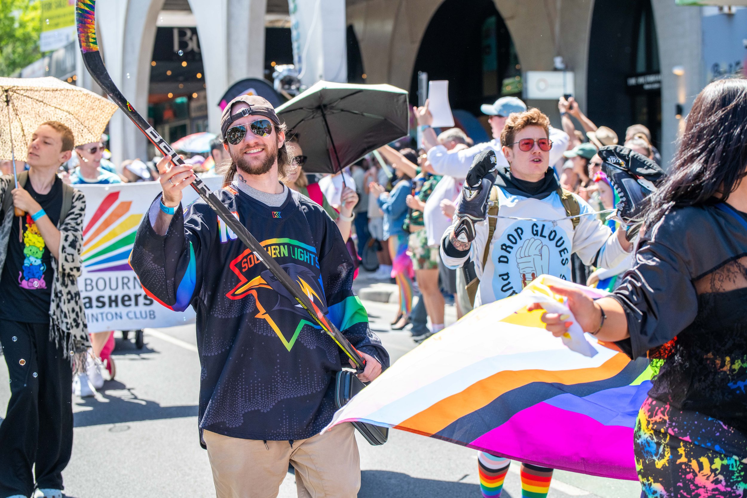 Ahuman wields an ice hockey stick and smiles at the camera.