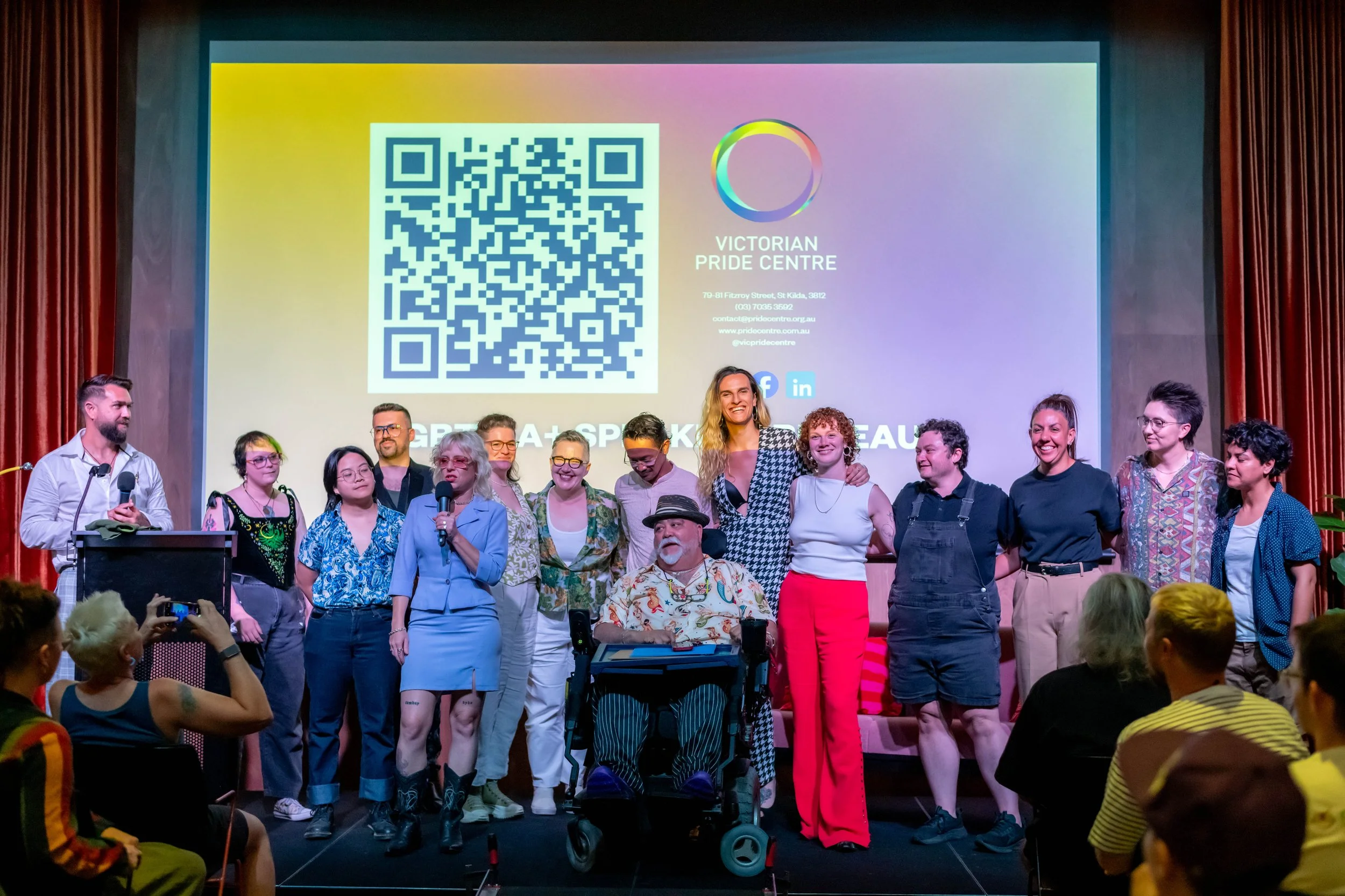 A of the evenings speakers are lined up smiling at the audience.