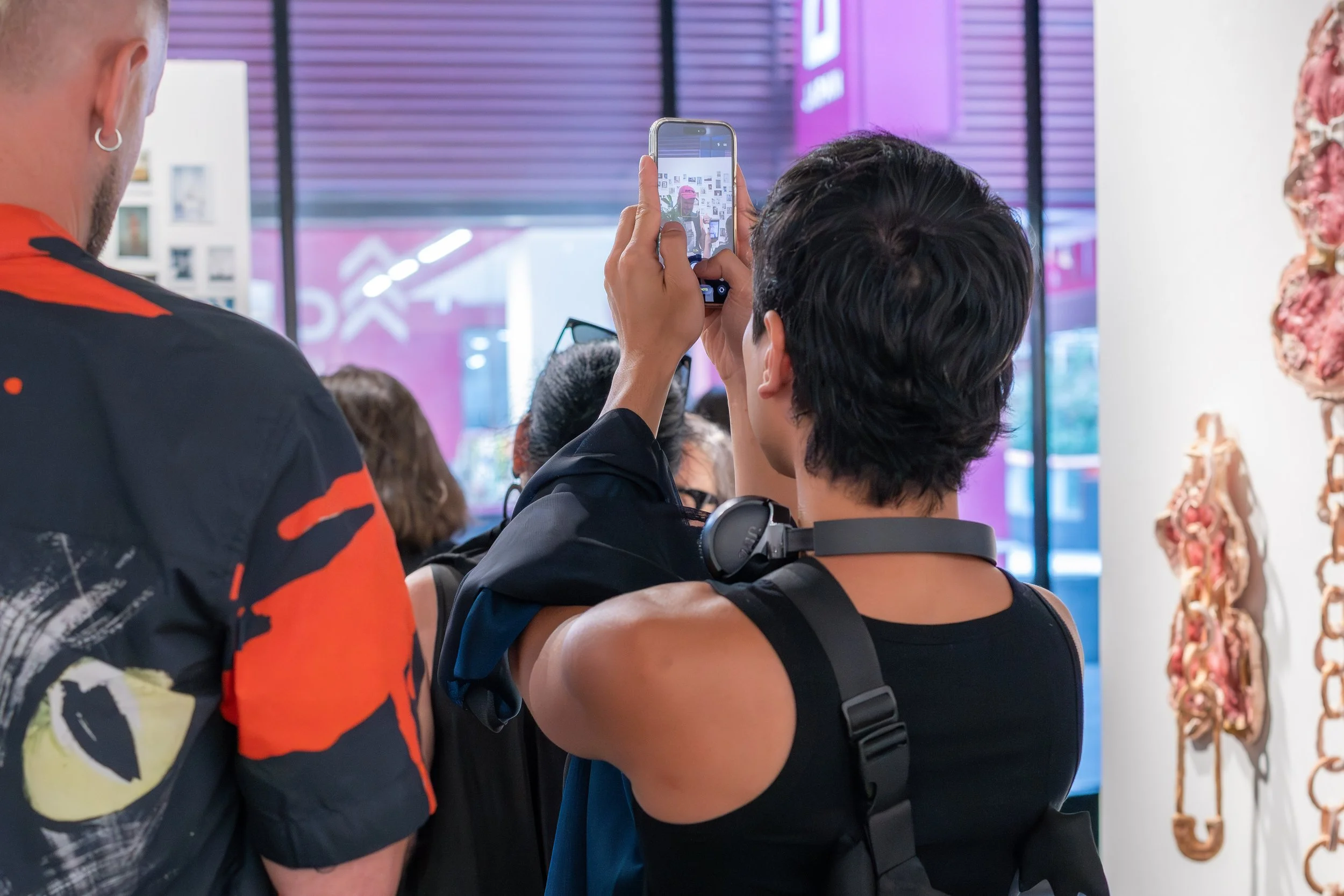 A human is taking a photo with their phone of artwork.