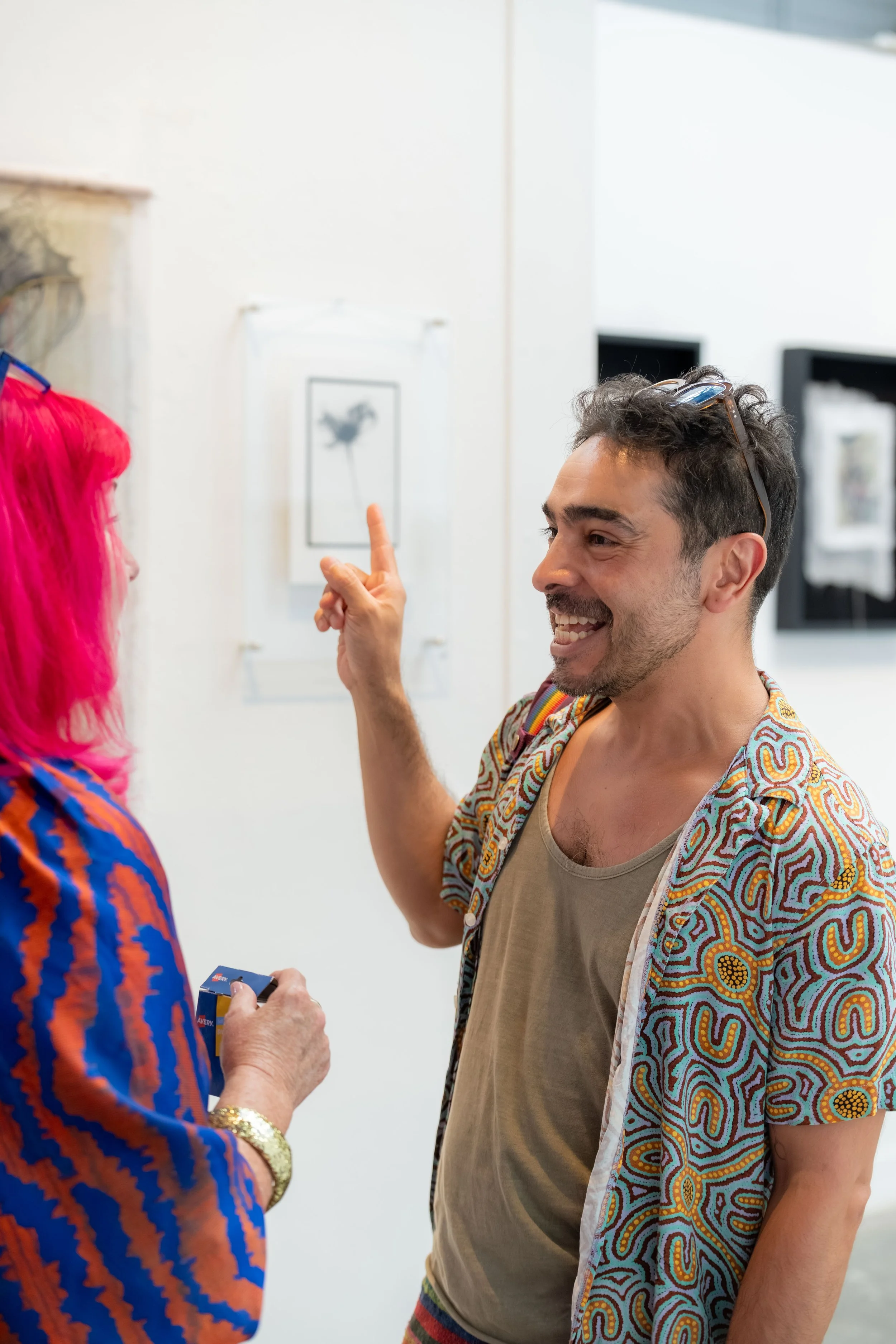 Ulises Resendiz smiles and points to an artwork.