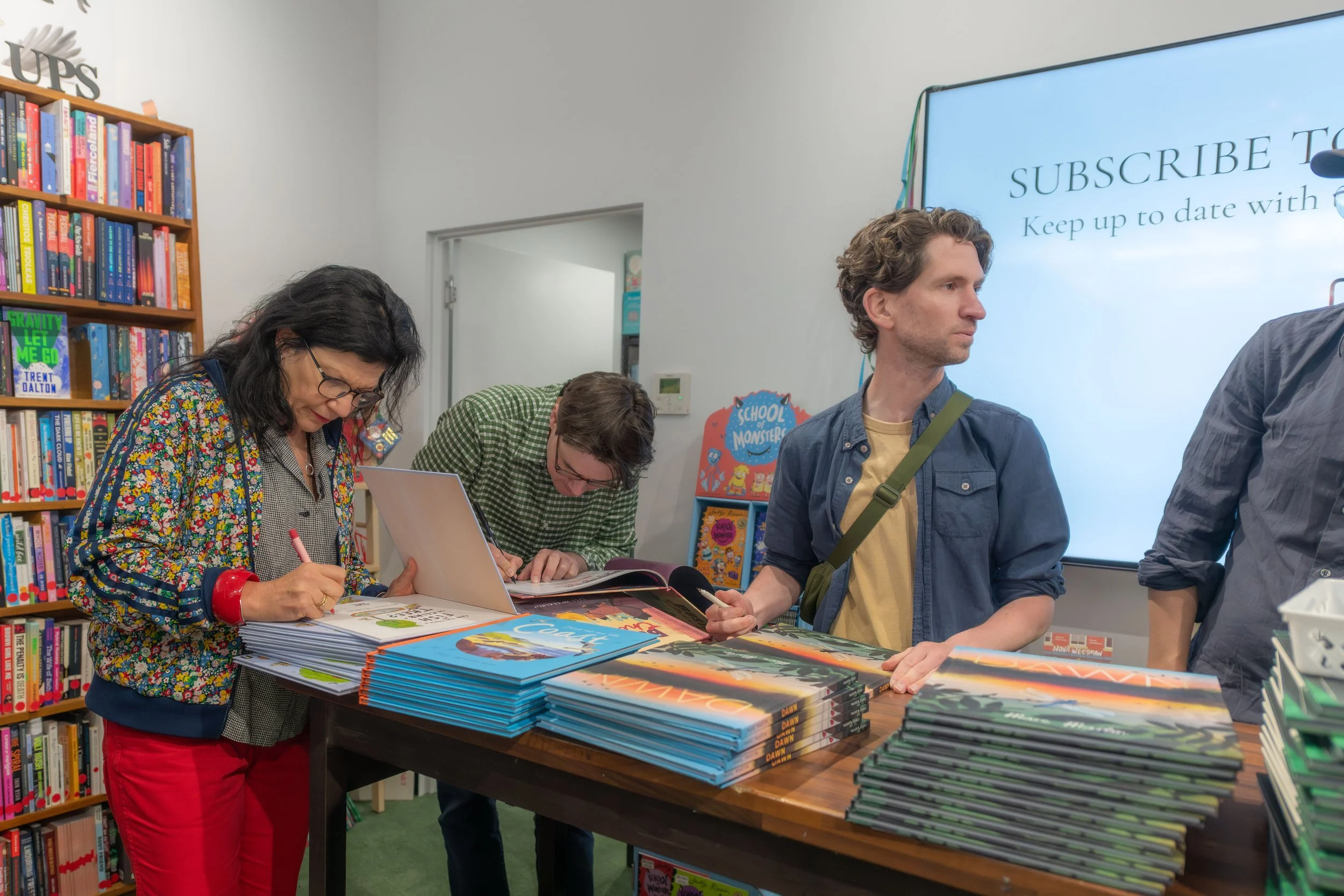 Authors are signing large stacks of books.