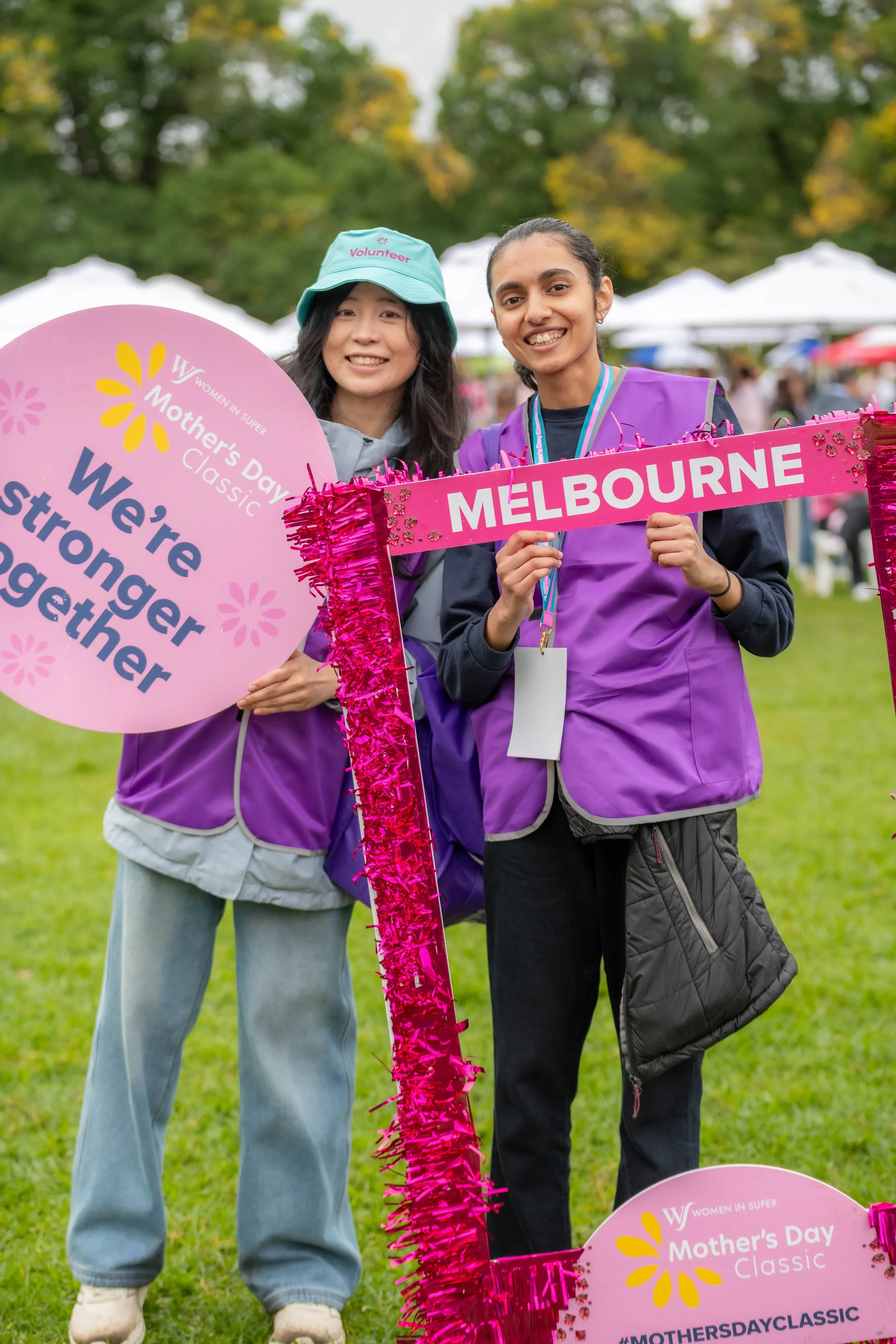 Two volunteers hold up signs and pose for the camera.