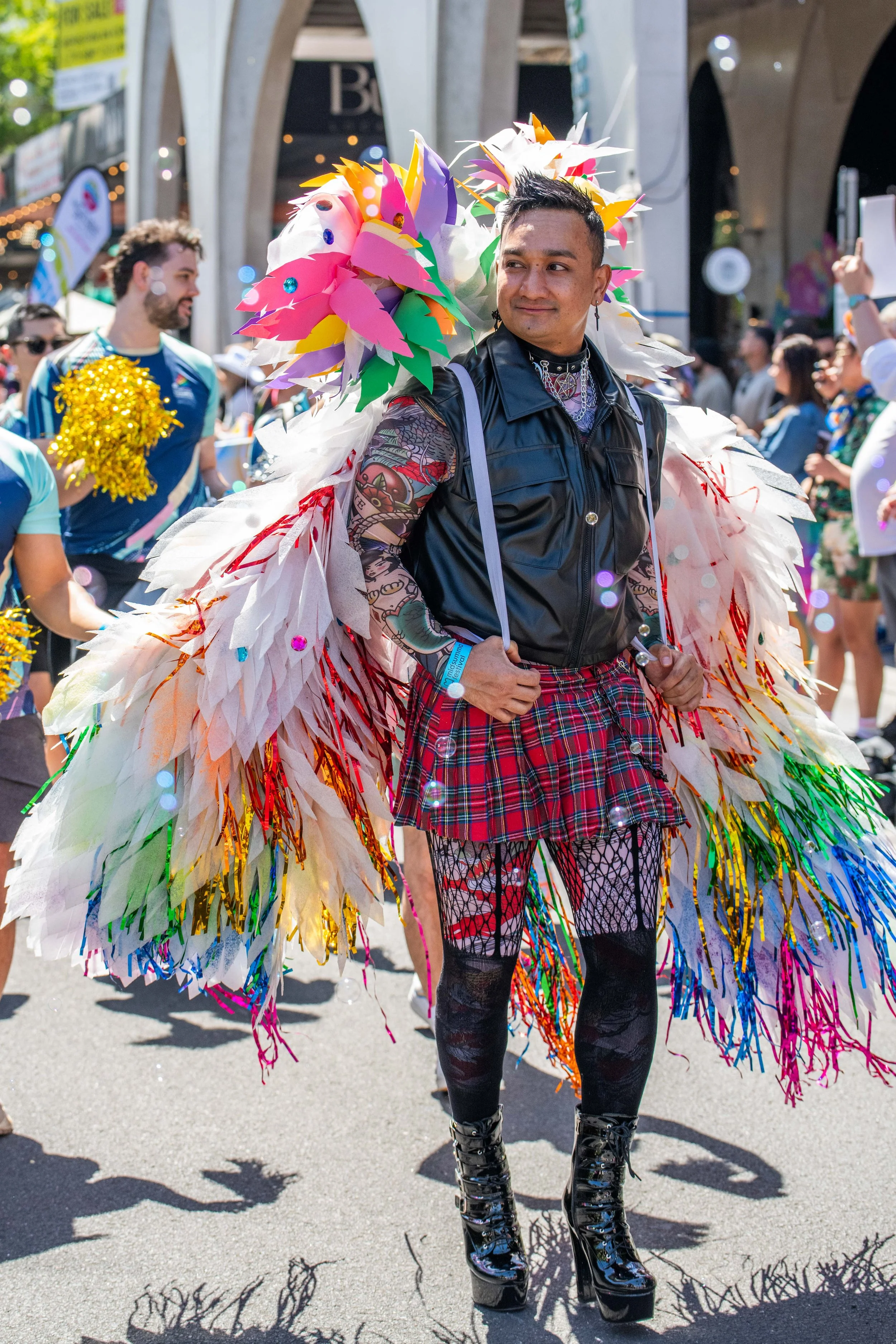 Ahuman is adorned with large wite feathers with rainbow enmeshed within.