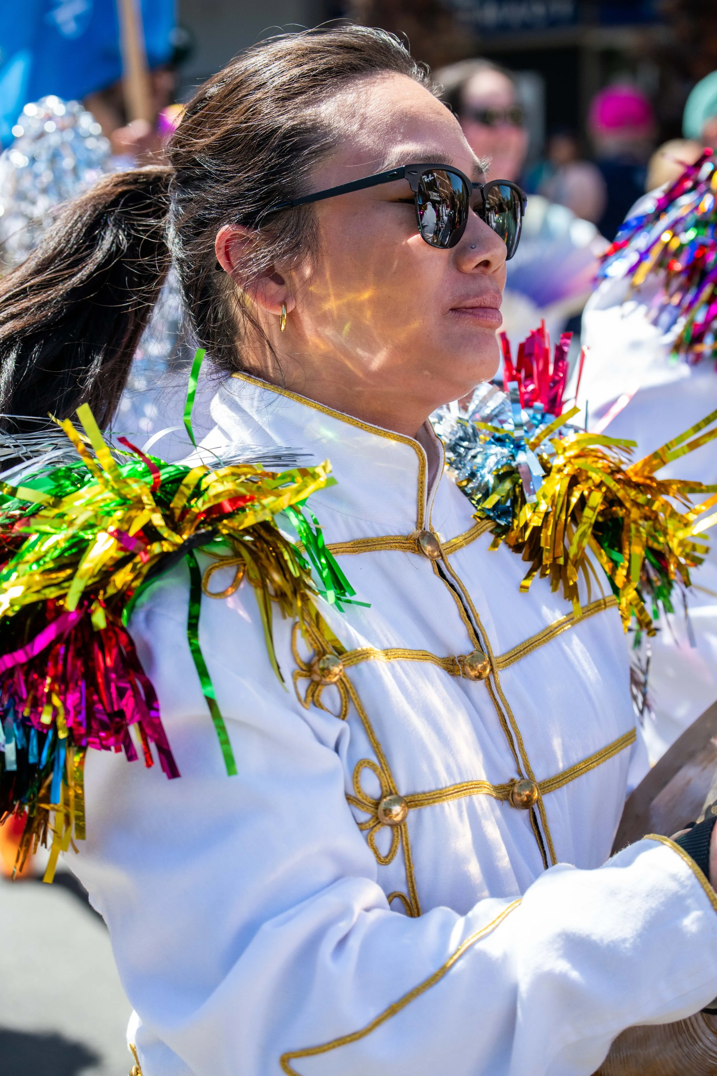 A band member wears rainbow shoulder pads that reflect on their face.