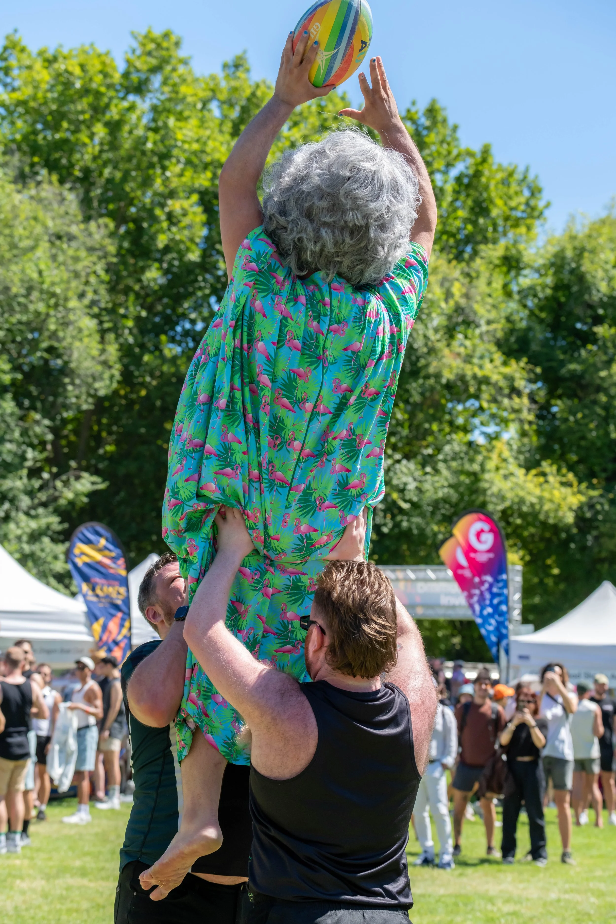 Drag queen Frock Hudson is being lifted into the air whilst catching a rugby union ball.