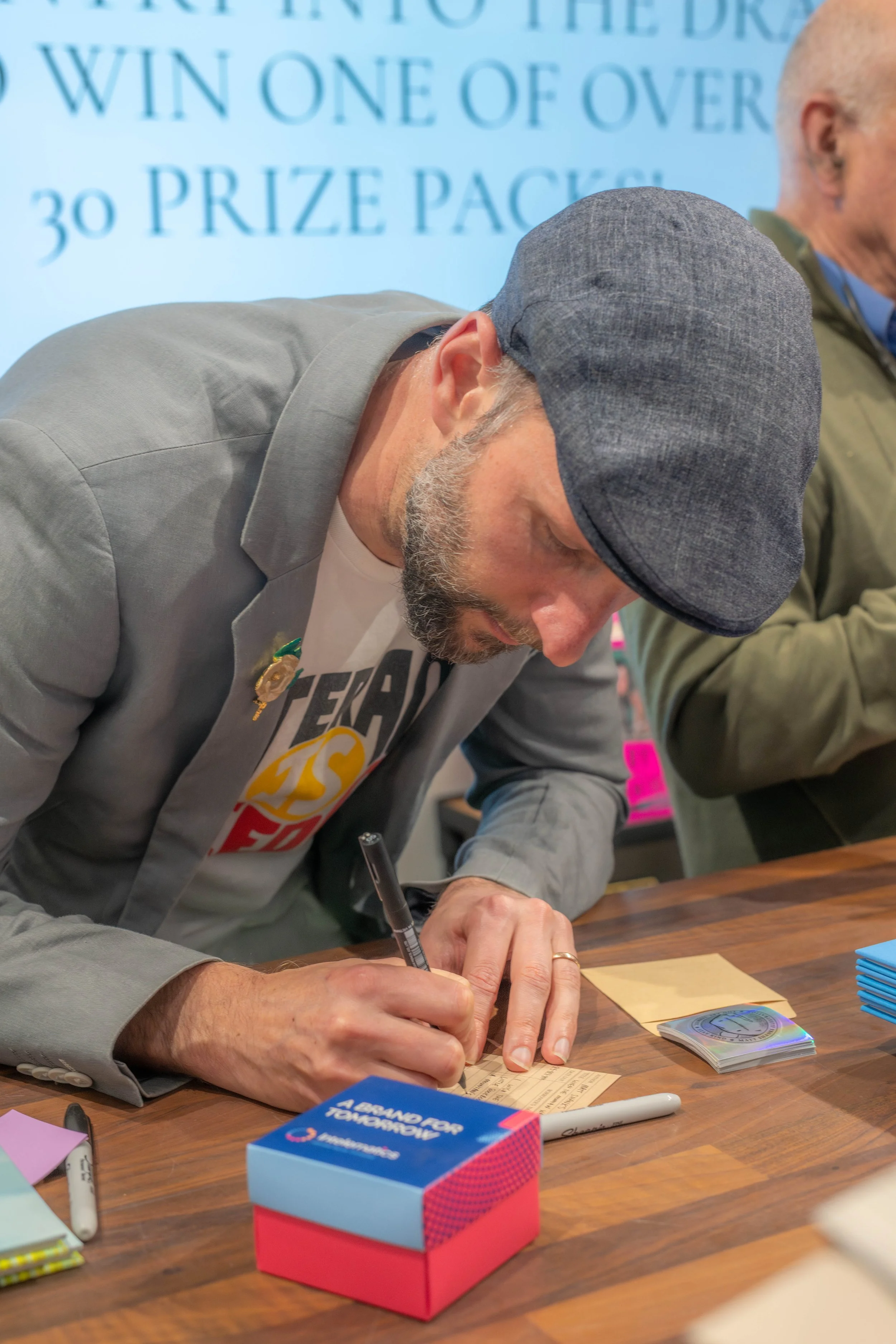 A human bends down as they sign a card.
