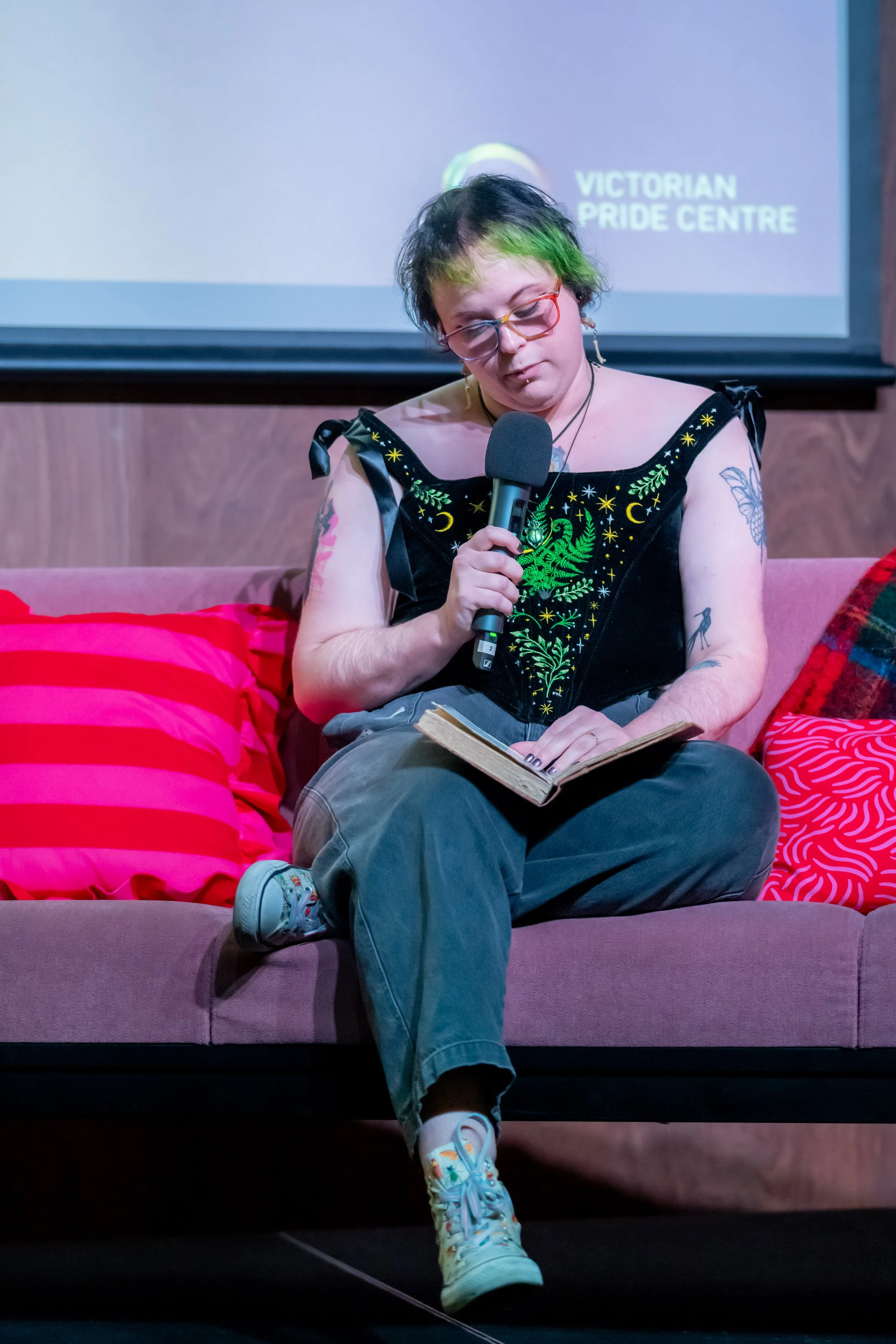 A human wearing a velvet top looks down as they give a talk.