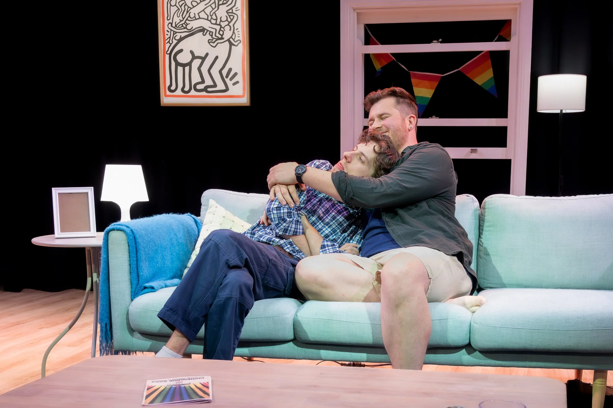 Two humans hug on a couch.