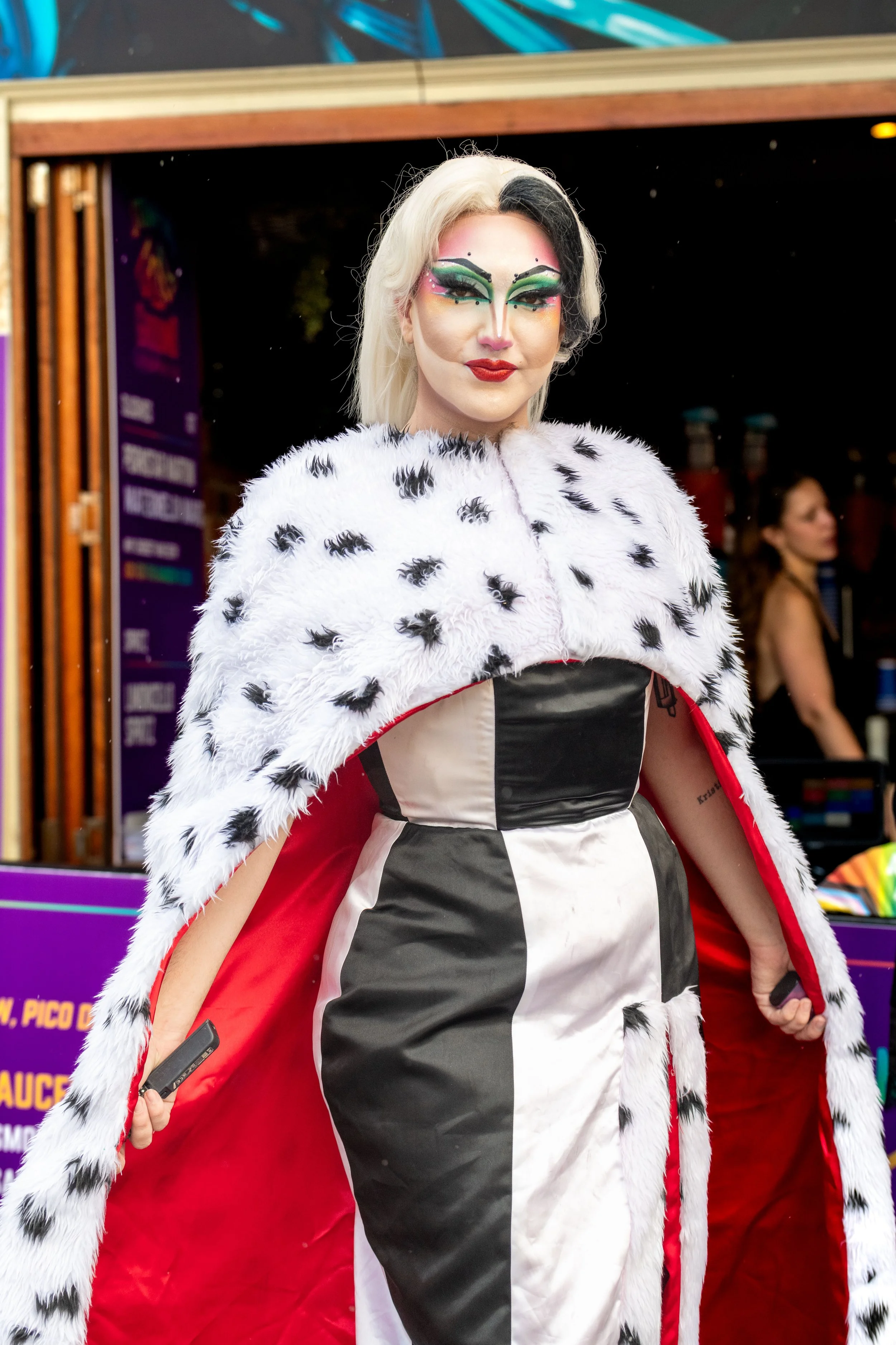 A drag queen with split black and white wig and queen fur cape poses for the camera.
