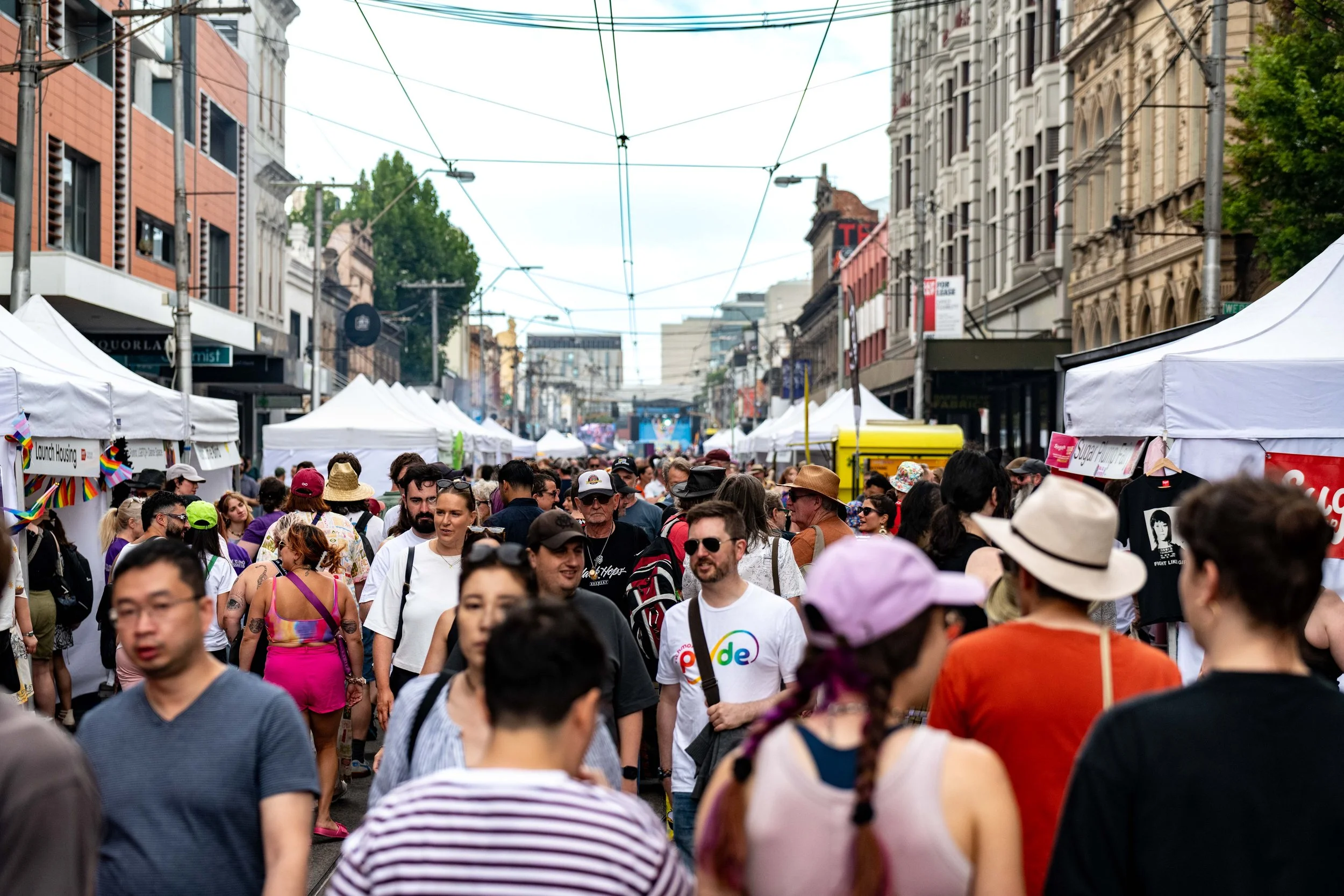 A crowded street full of people as they walk past stalls.