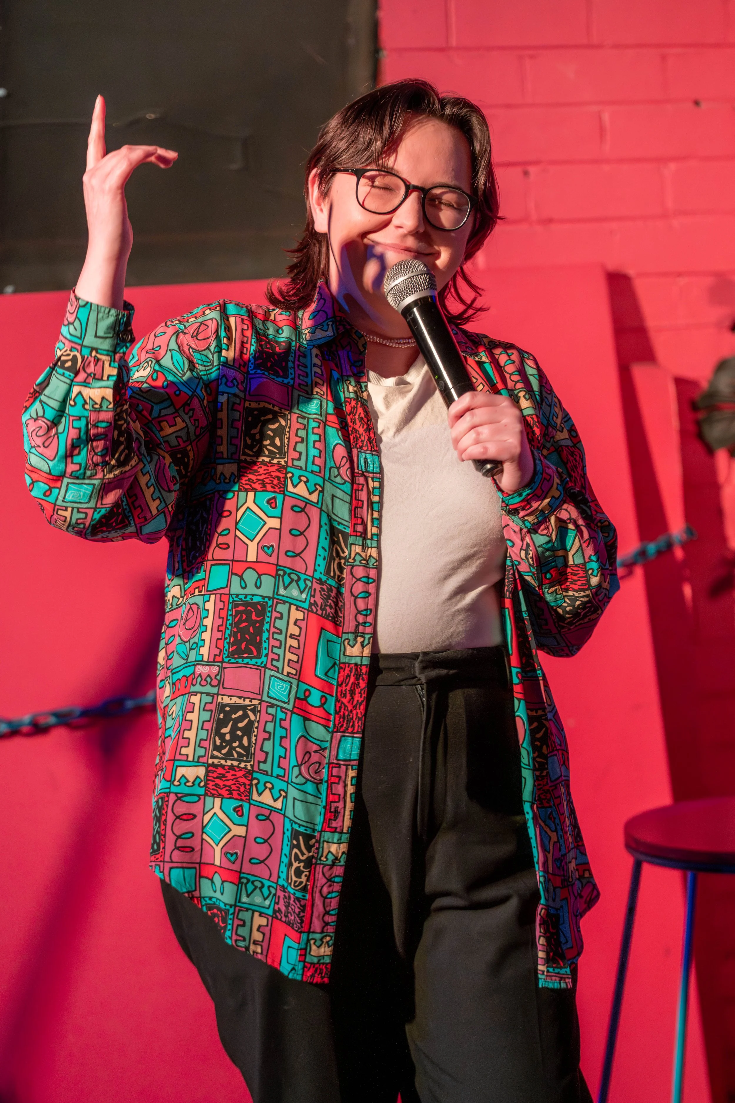 A human speaks into the microphone closing their eyes and pointing a finger into the air.