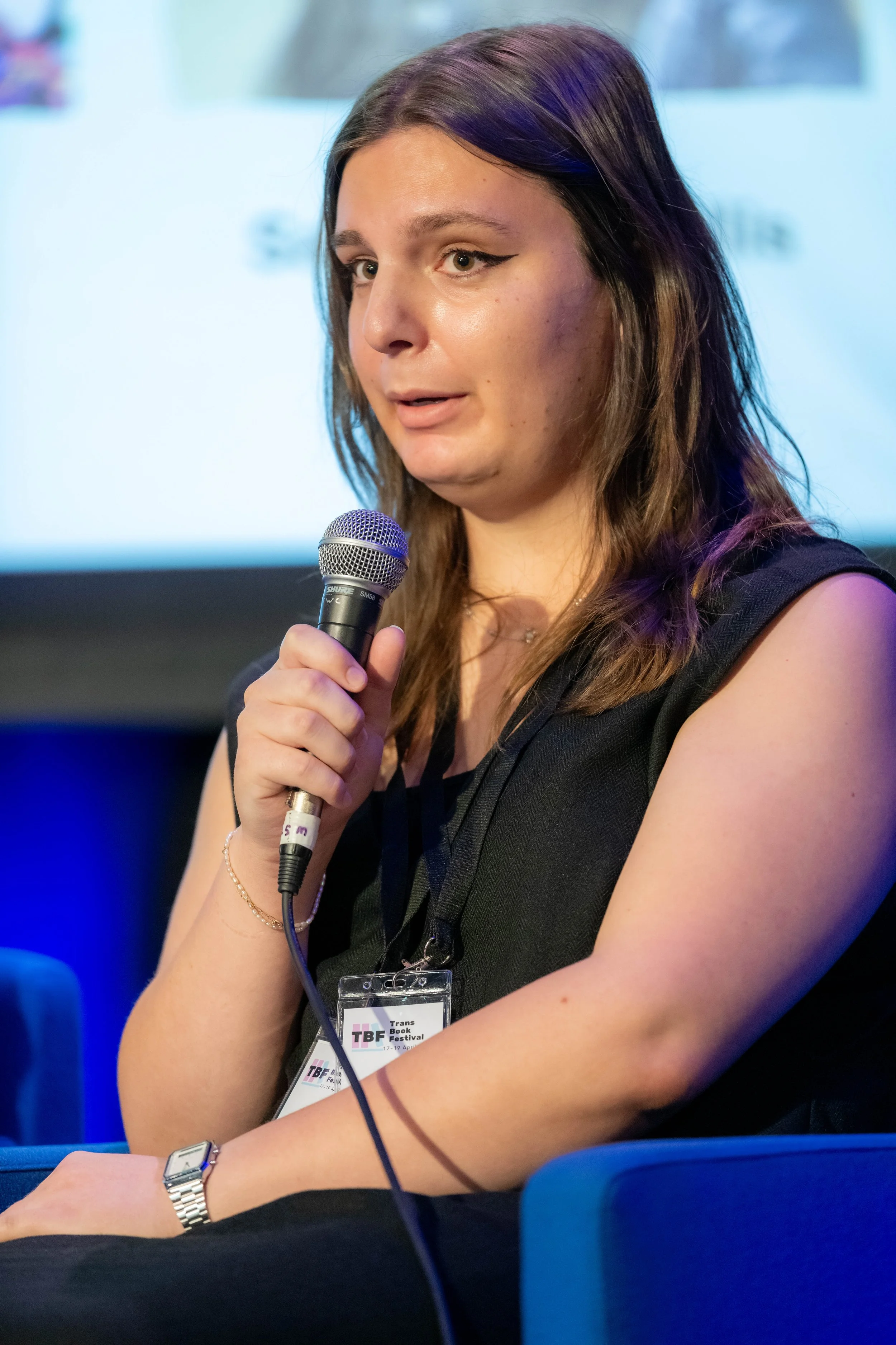 A panelist in a black dress speaks into a microphone