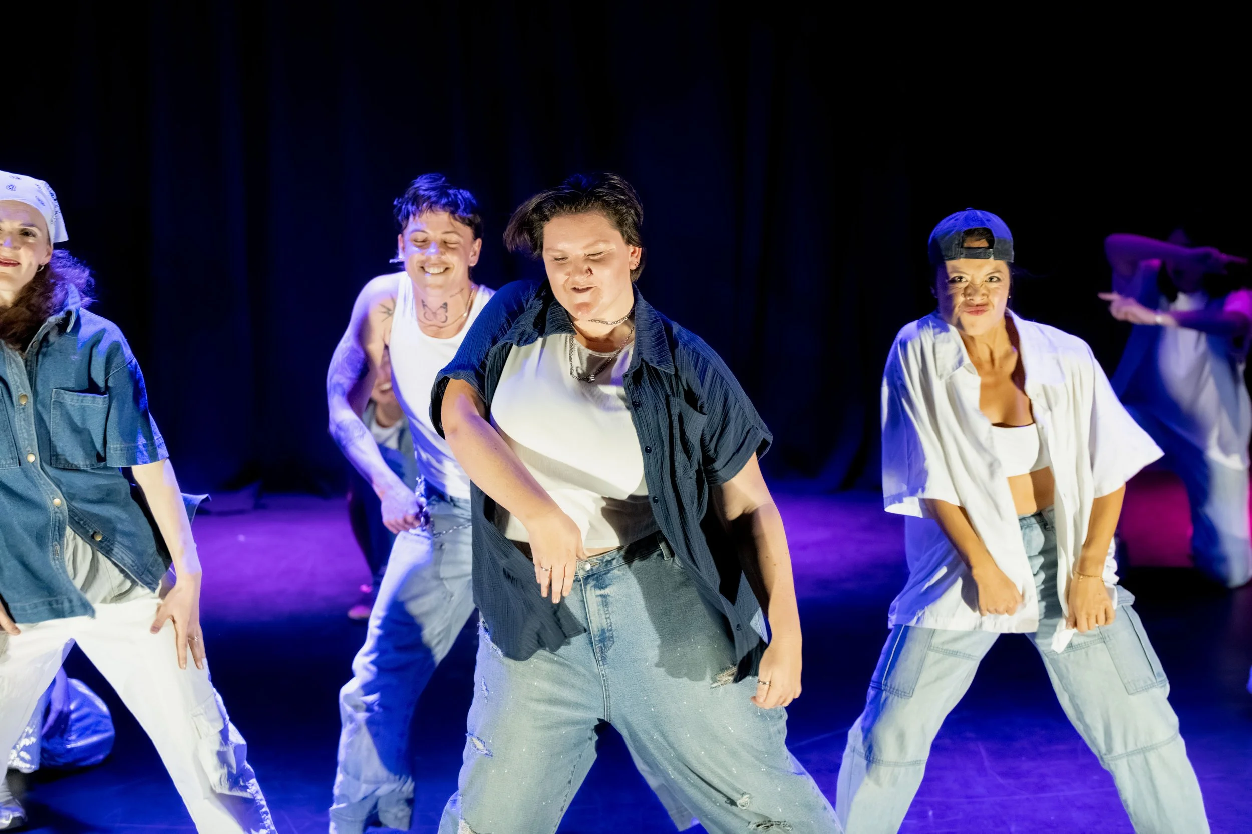 Four dancers in denim can be seen leaning to the left.