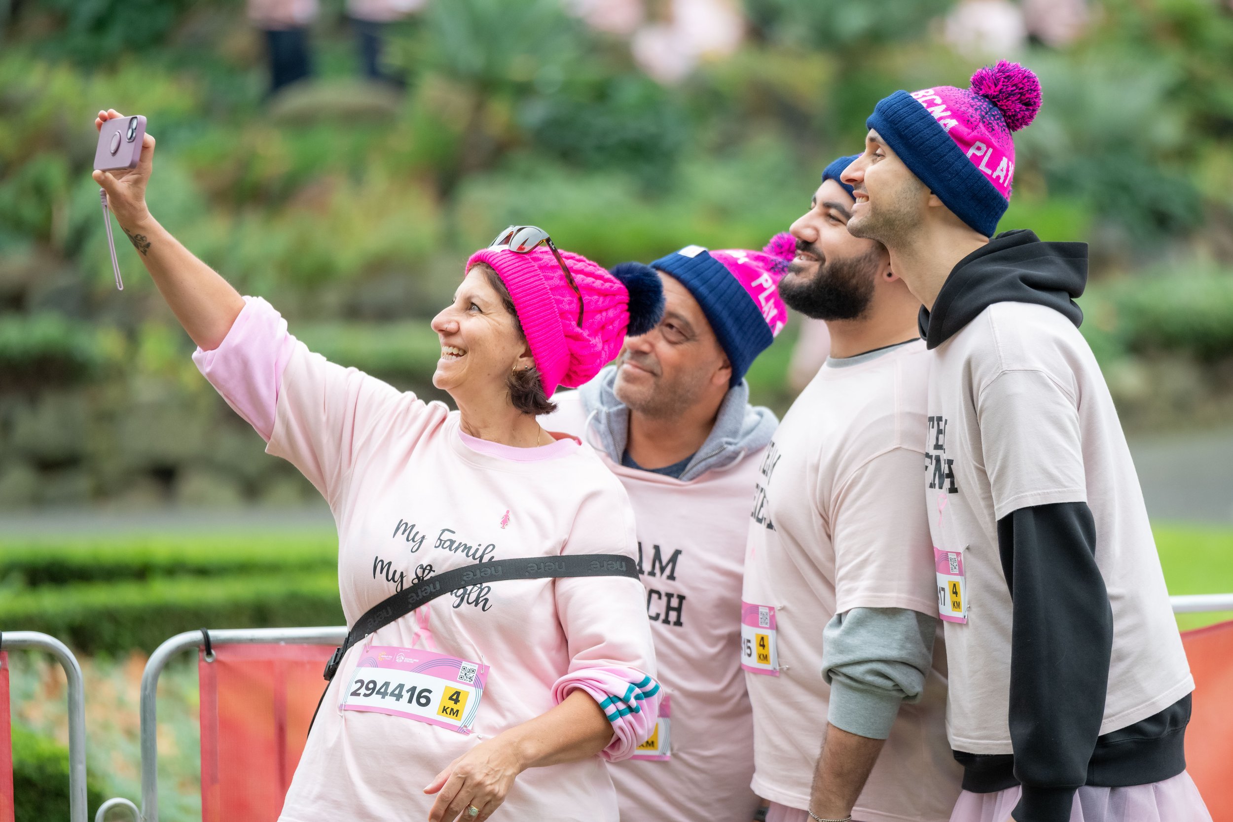 A group of racegoers wearing memorial tees take a selfie with their phone.