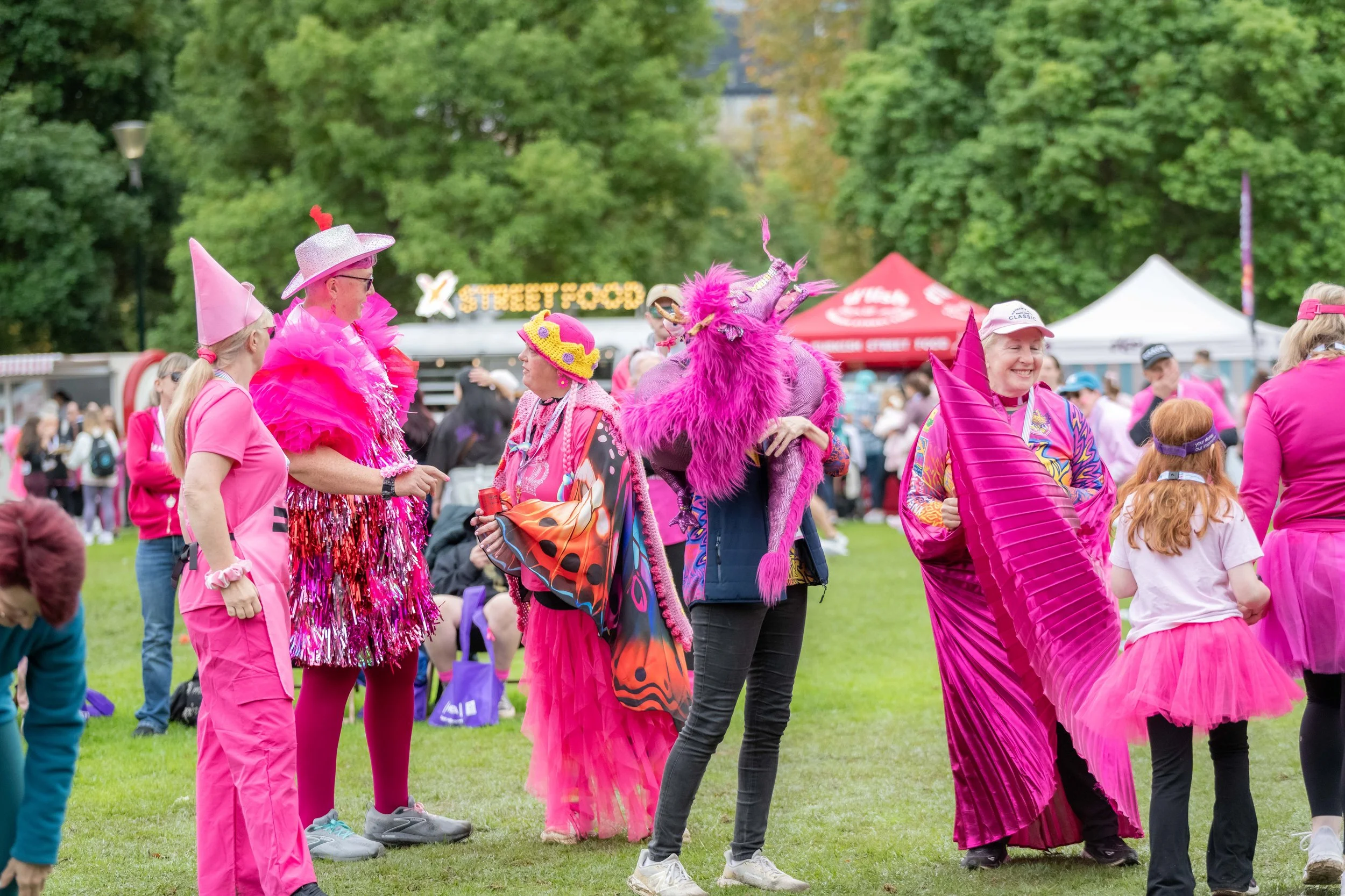 Racegoers wearing all sorts of pink outfits dance.