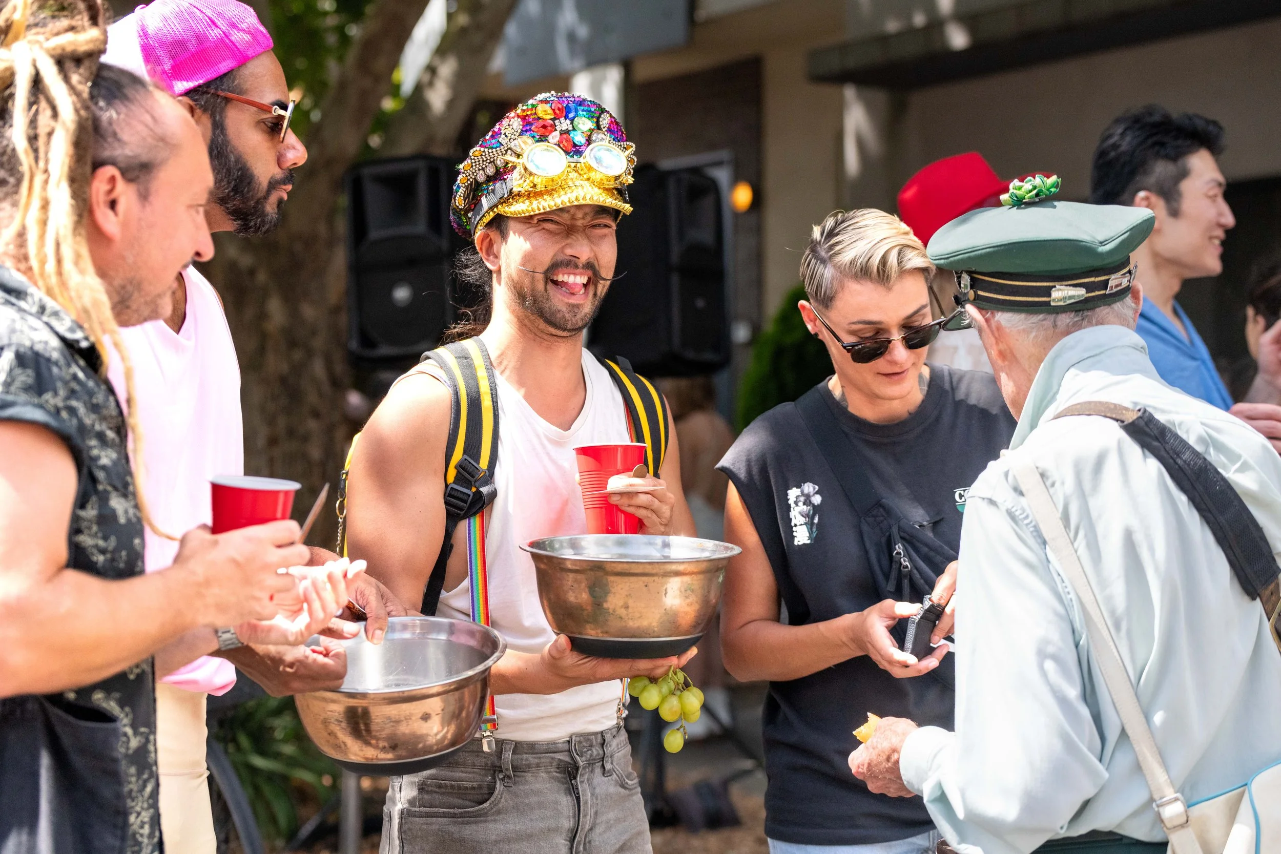 Humans hilding bowls smile as a human in a tram conductor uniform hands out tickets.
