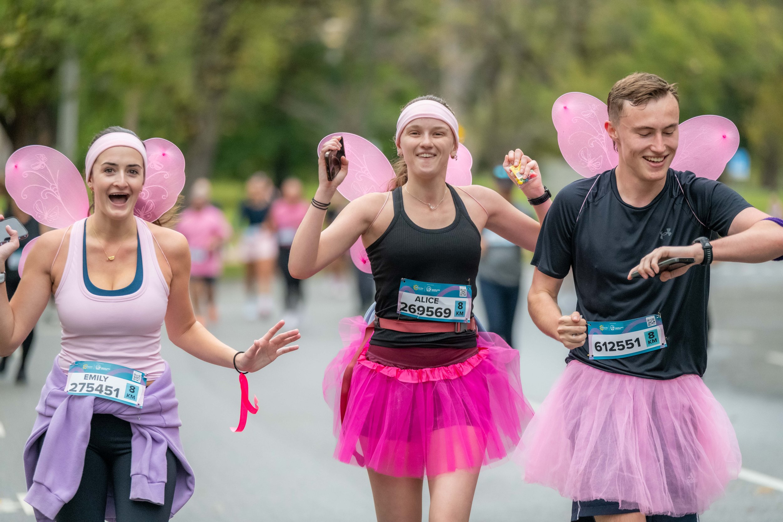 Three racegoers wearing pink butterfly wings.