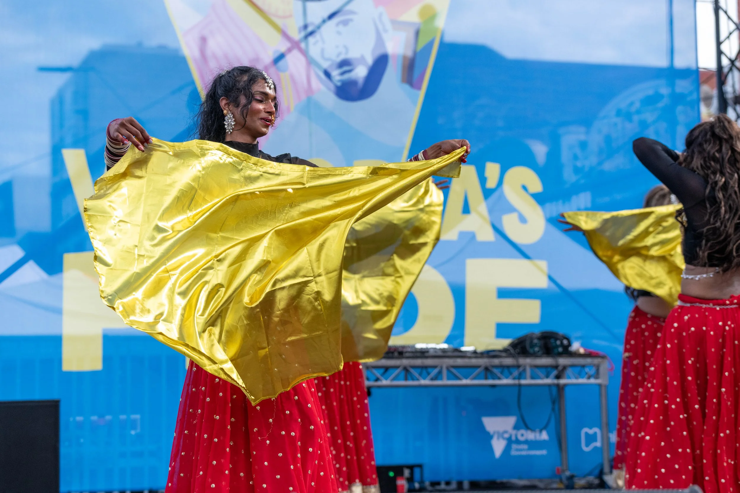 Dancers from Karma Dance wave golden flags in the air in front of them.