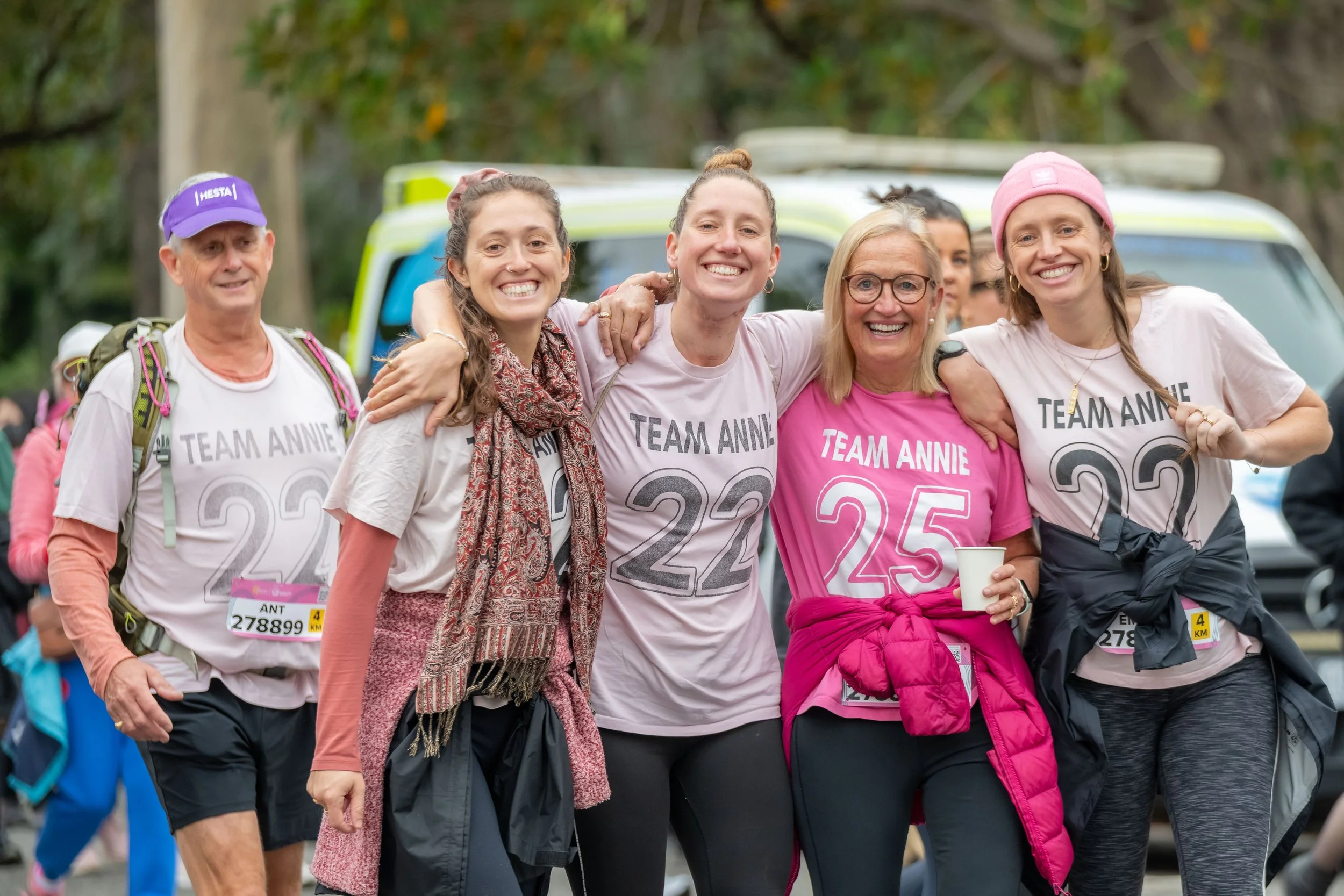 Five racegoers hug and wear pink "Team Annie" tees.