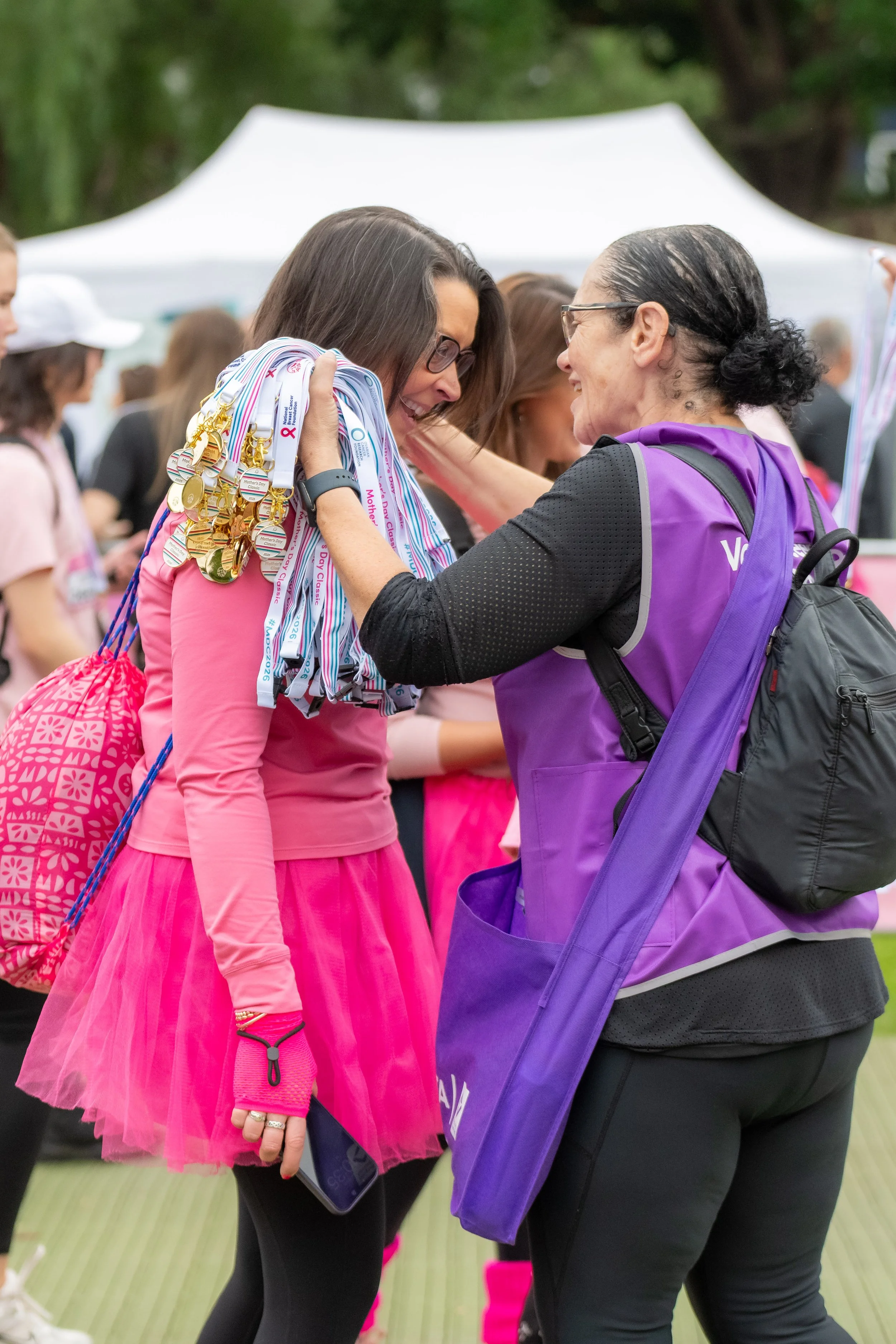A volunteer places a medal around a racegoers neck.