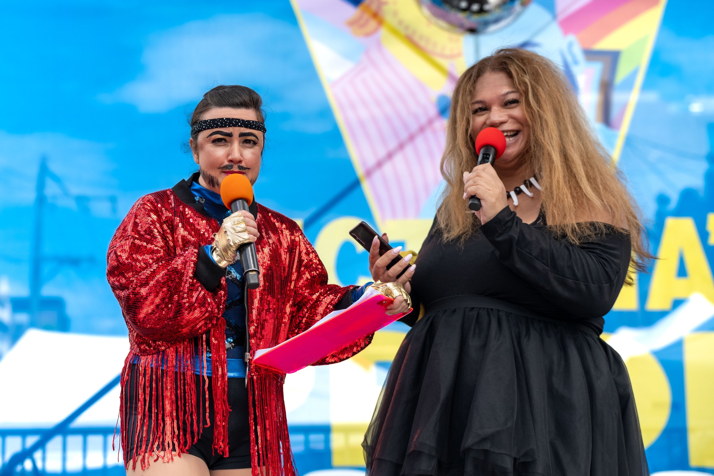 Miss Katalyna and drag king Donnie Piccolo talk into a microphone.