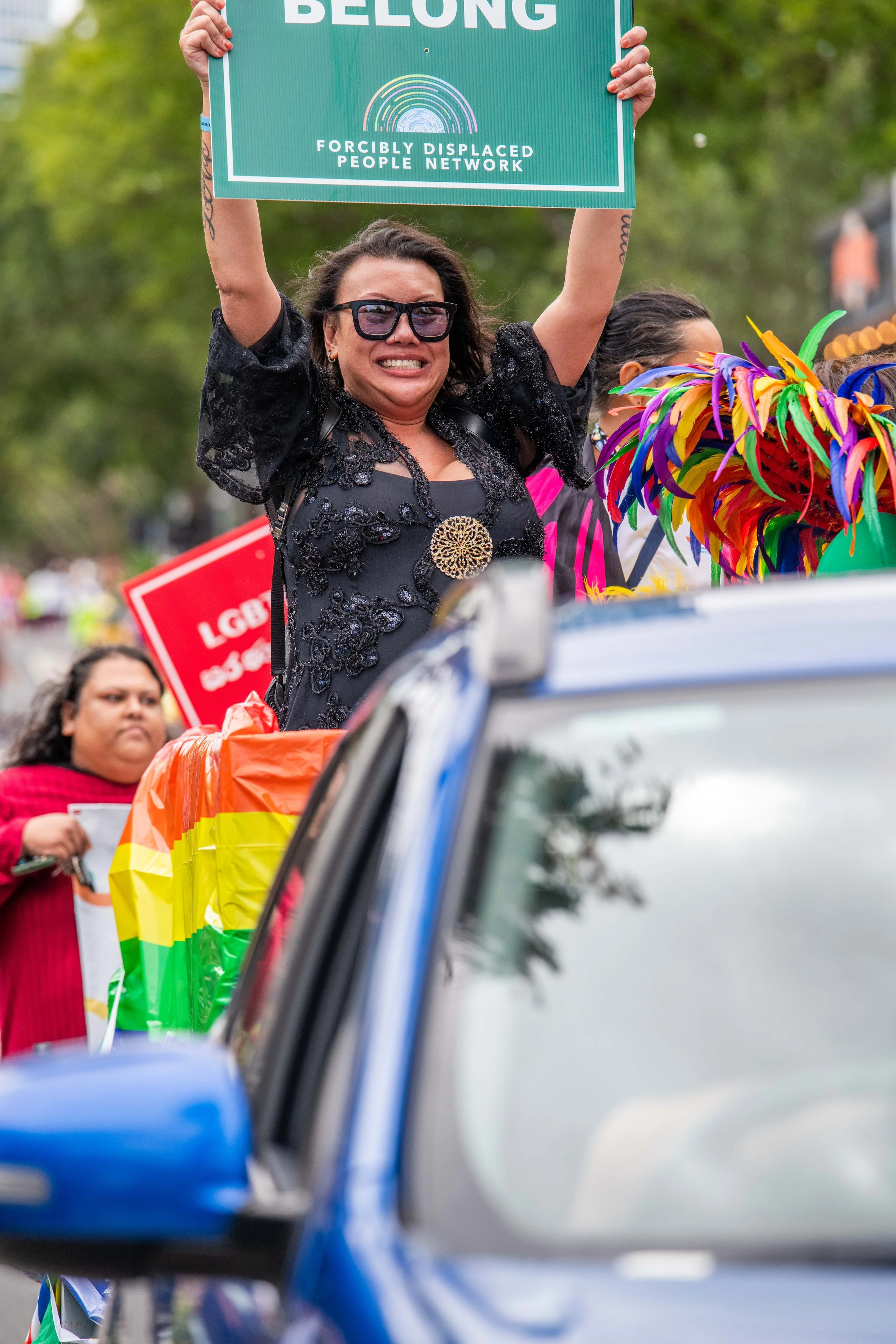 A human rides in the back of a trailer holding up a sign.