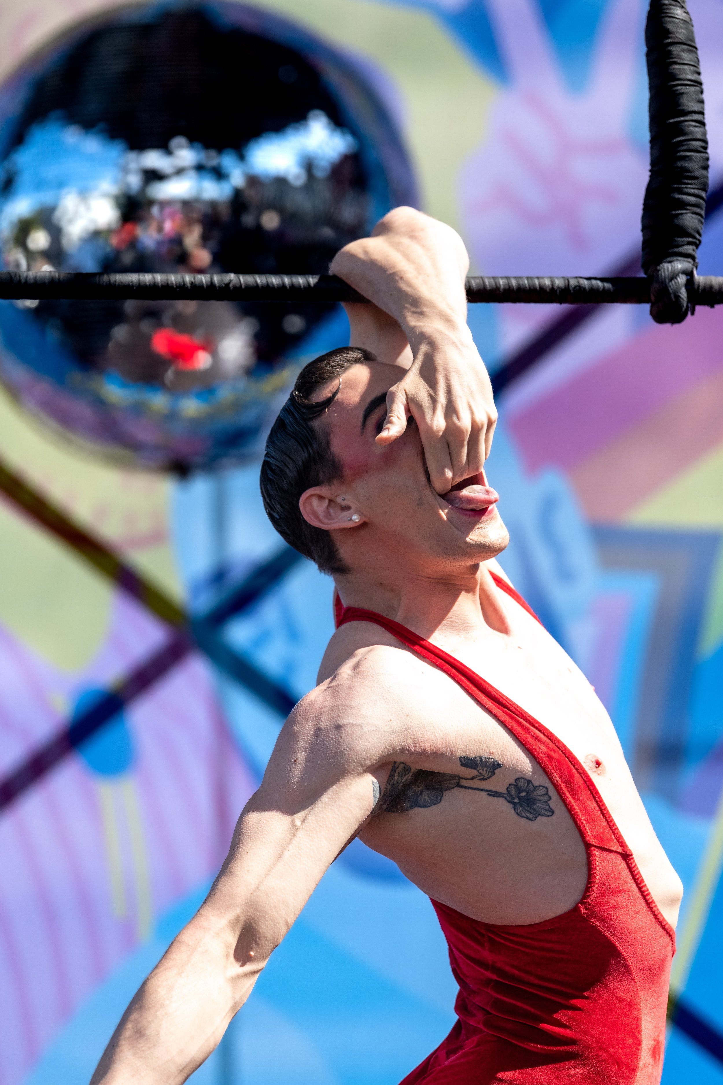 Jarred Dewey holds onto the trapeze whilst holding onto their mouth.