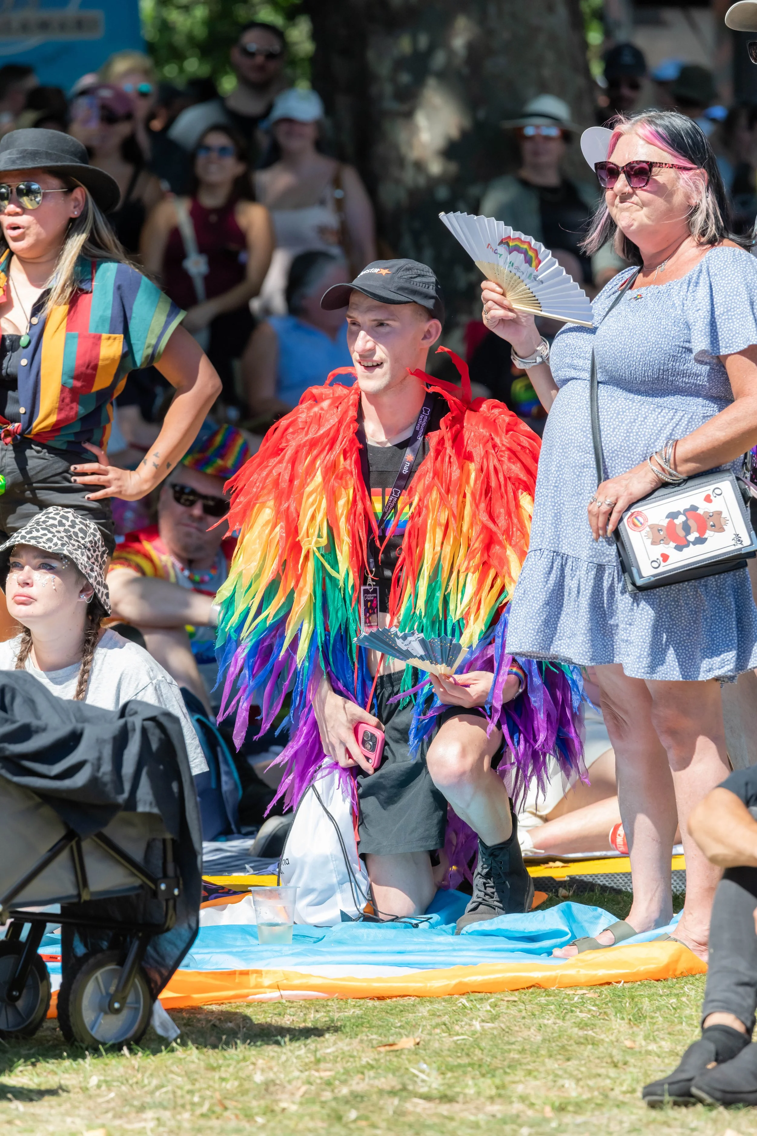 A human crouches wearing a shaggy rainbow outfit.