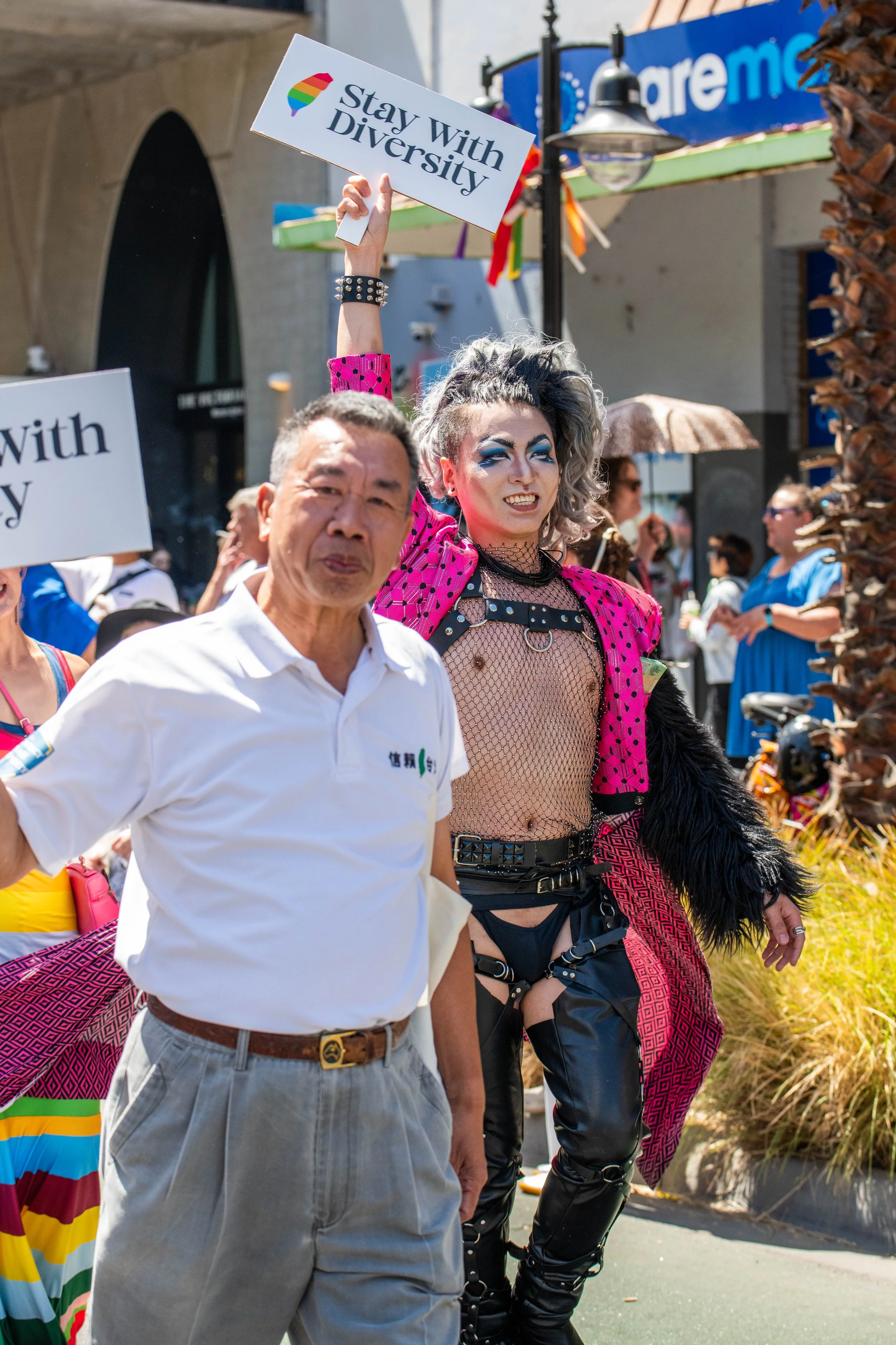 A human in pink jacket marches alongside a fellow human in white polo.