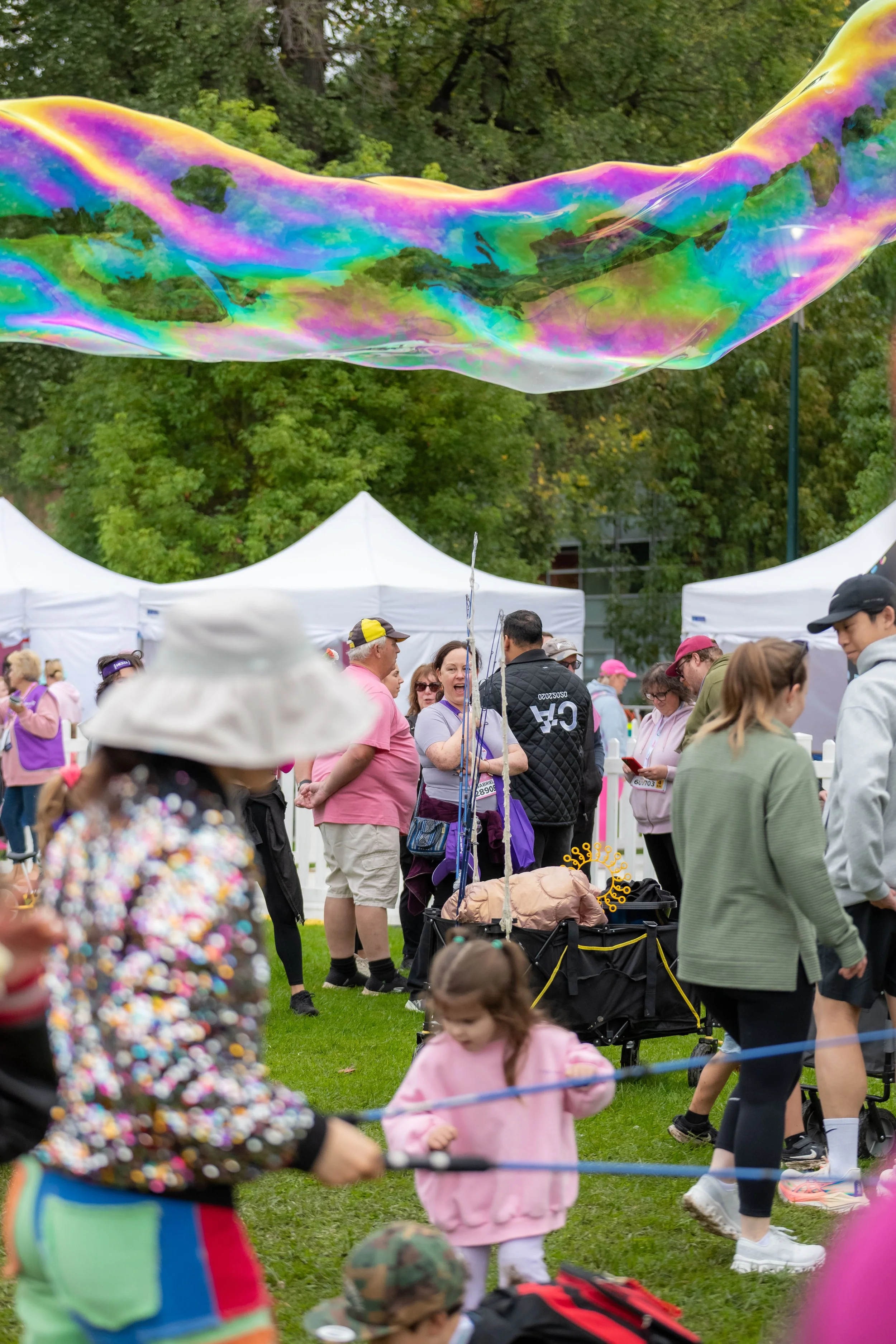 A large rainbow bubble crosses the top of the screen above racegoers heads.