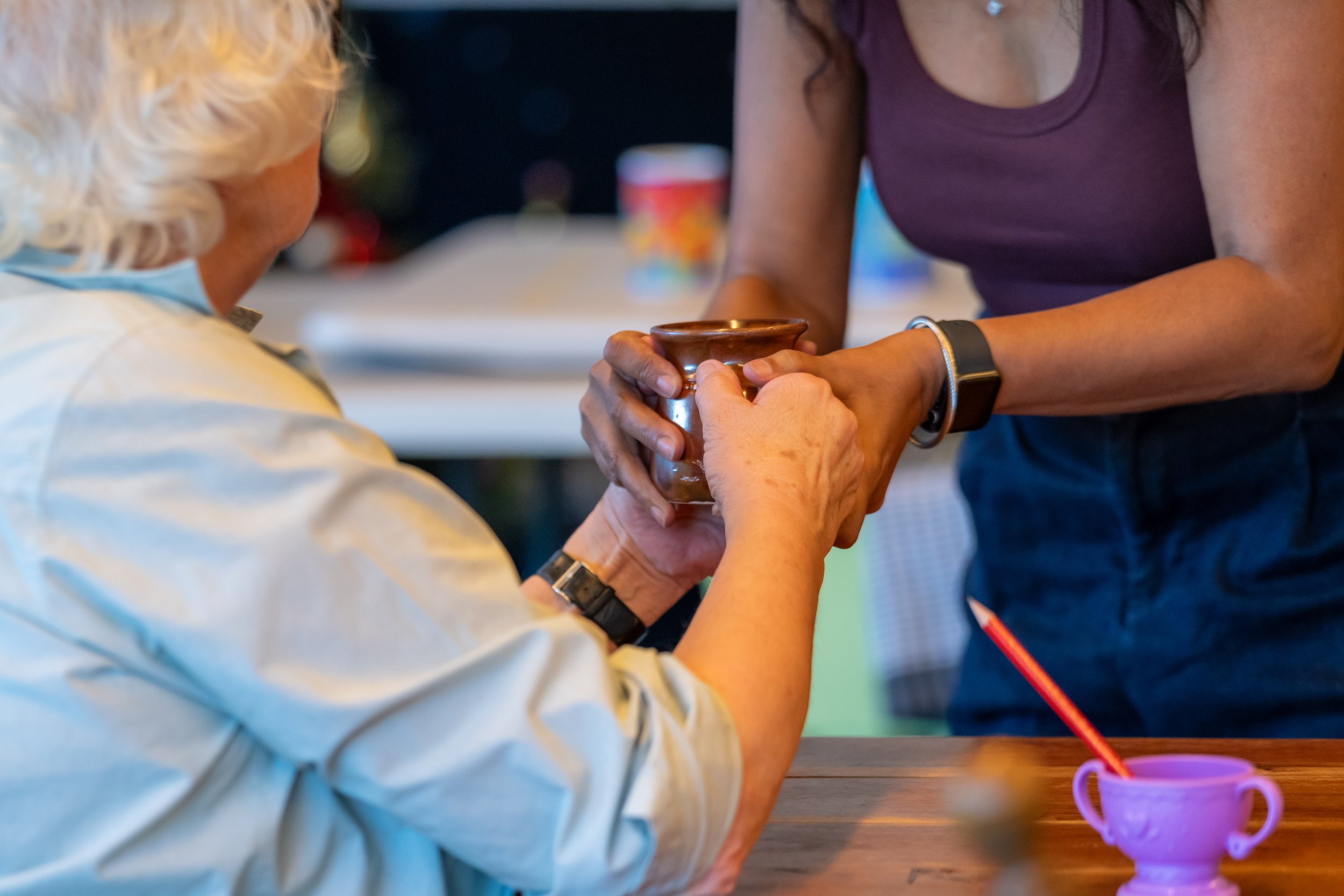 A close up of two people fighting over a brown mug. Their faces are out of shot, only their arms are in view.