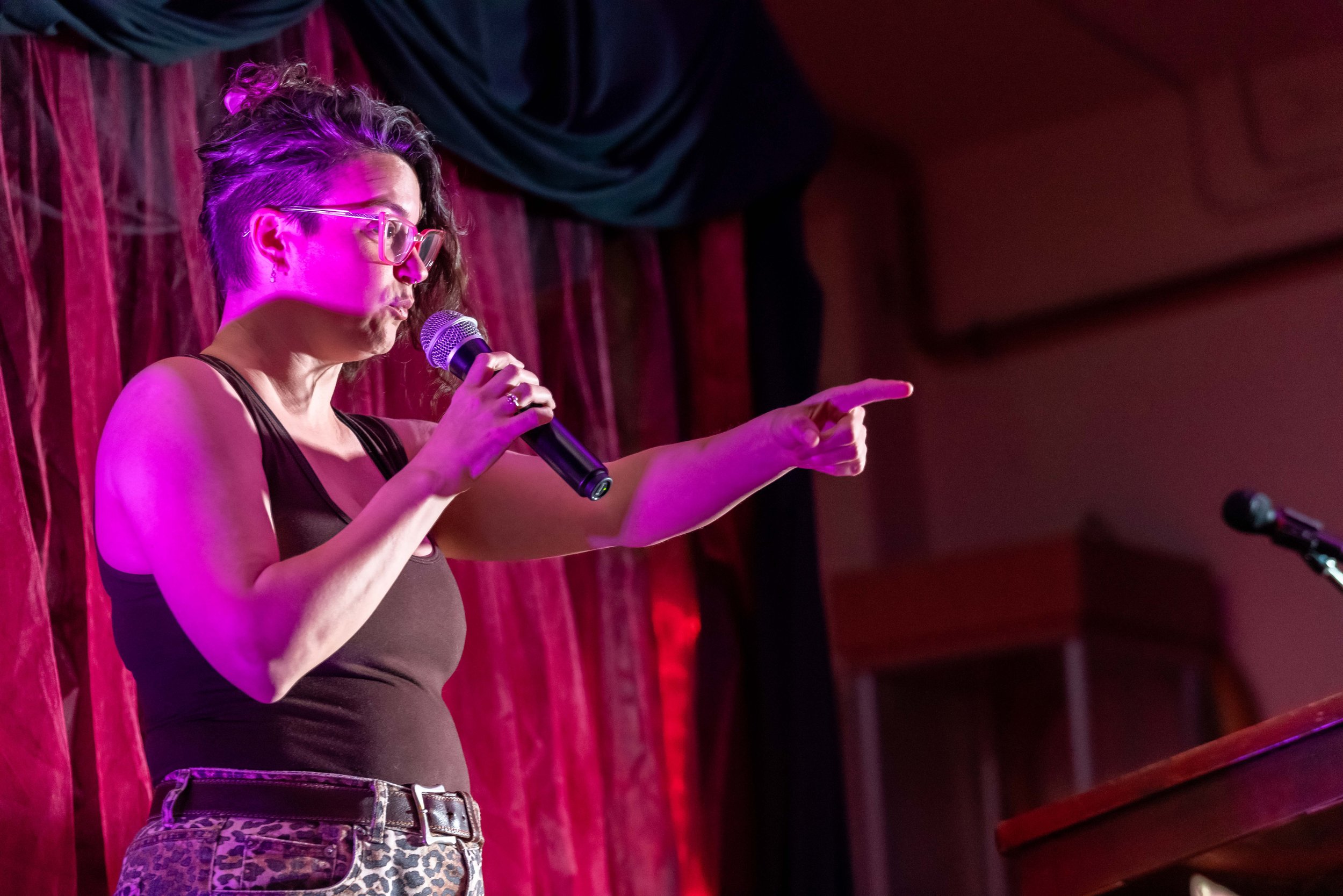 Fleasey Malay speaks into a microphone whilst pointing.