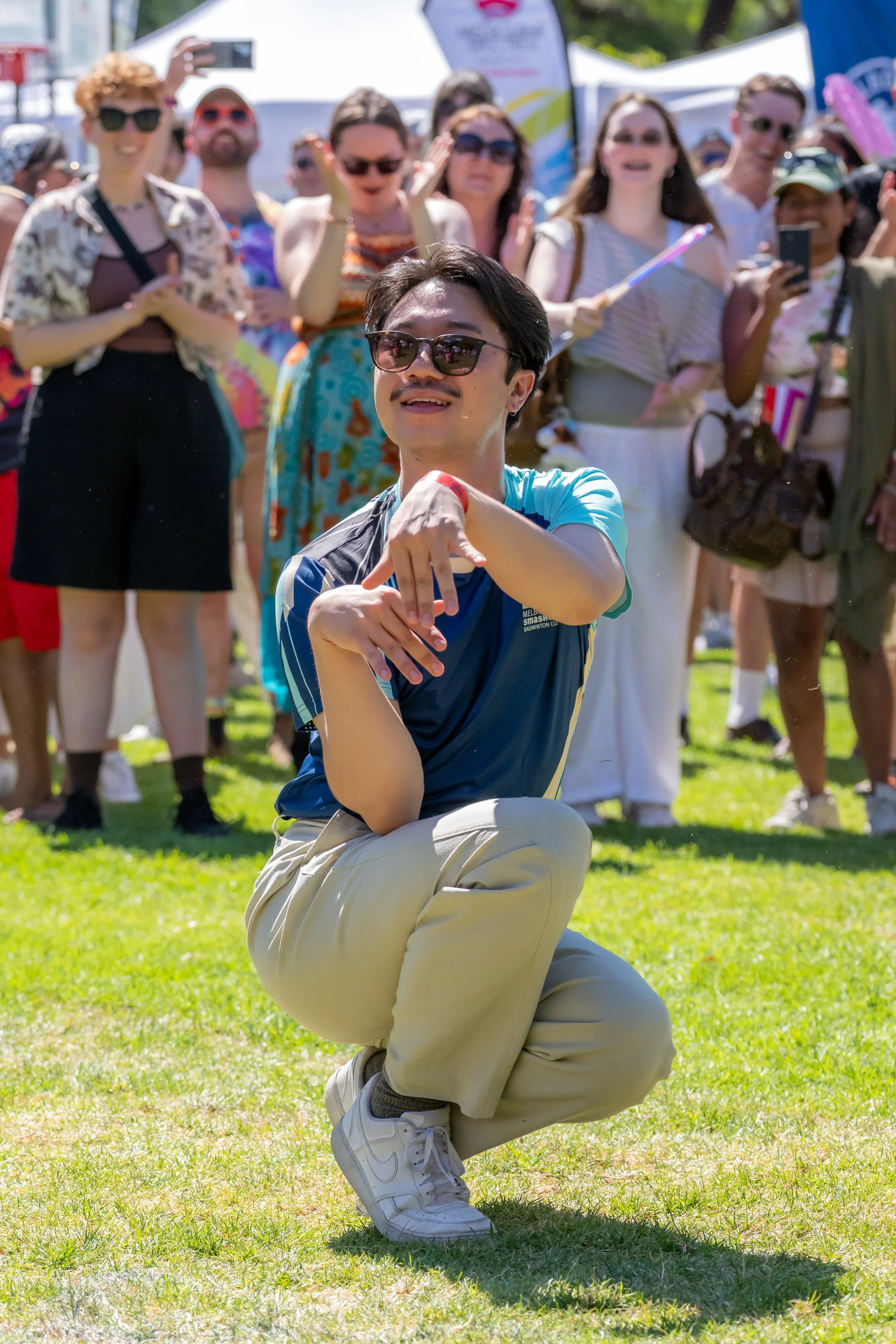 A human ball dances in a crouch as people look on.